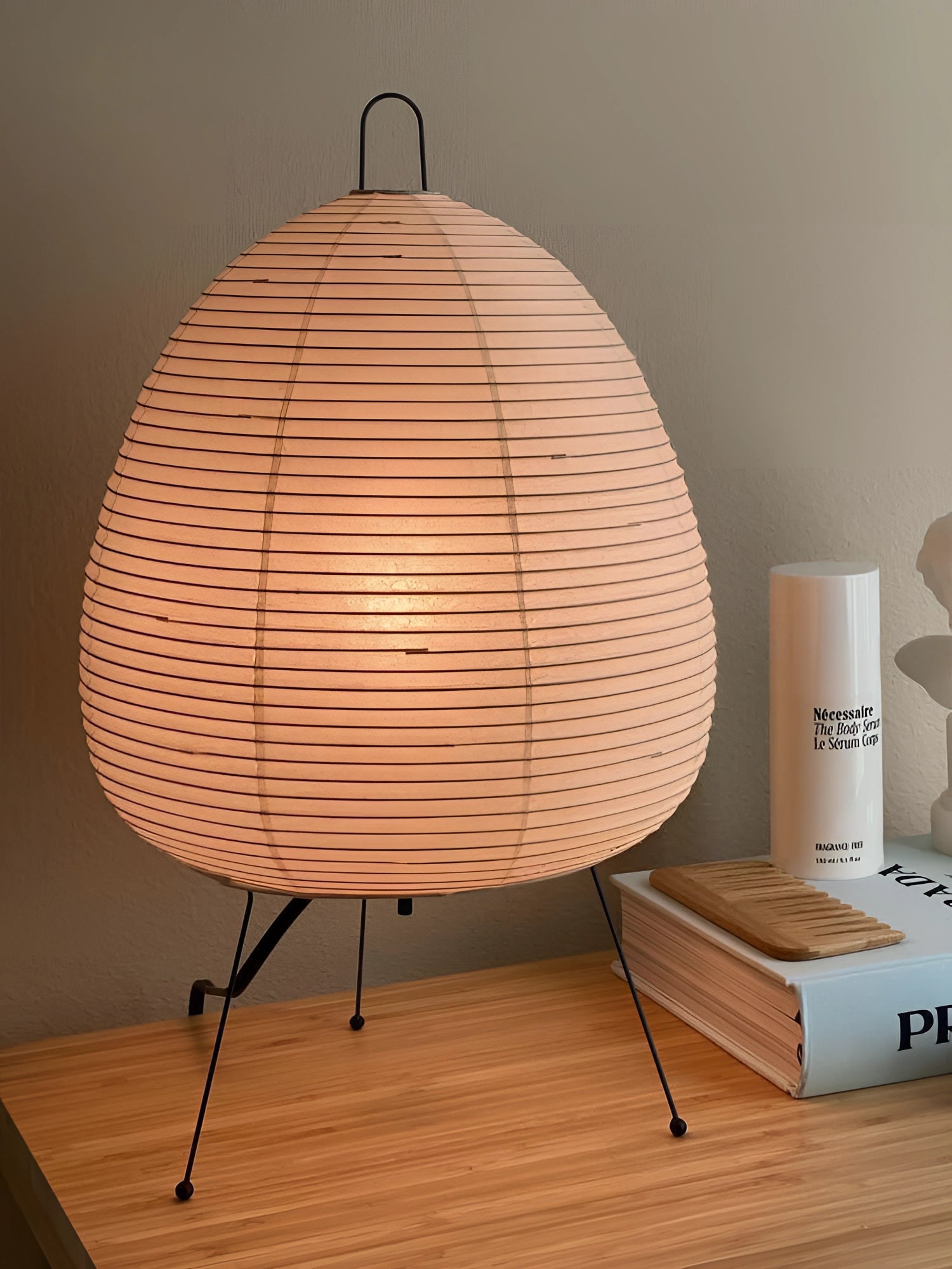 A sculptural tripod floor lamp with a unique beehive design, featuring a wooden base and a circular lampshade, adding an artistic statement to any room.