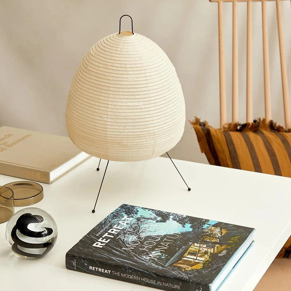 A uniquely designed Beehive Sculptural Tripod Floor Lamp with a wooden base, standing next to a modern table within a stylish interior setting.