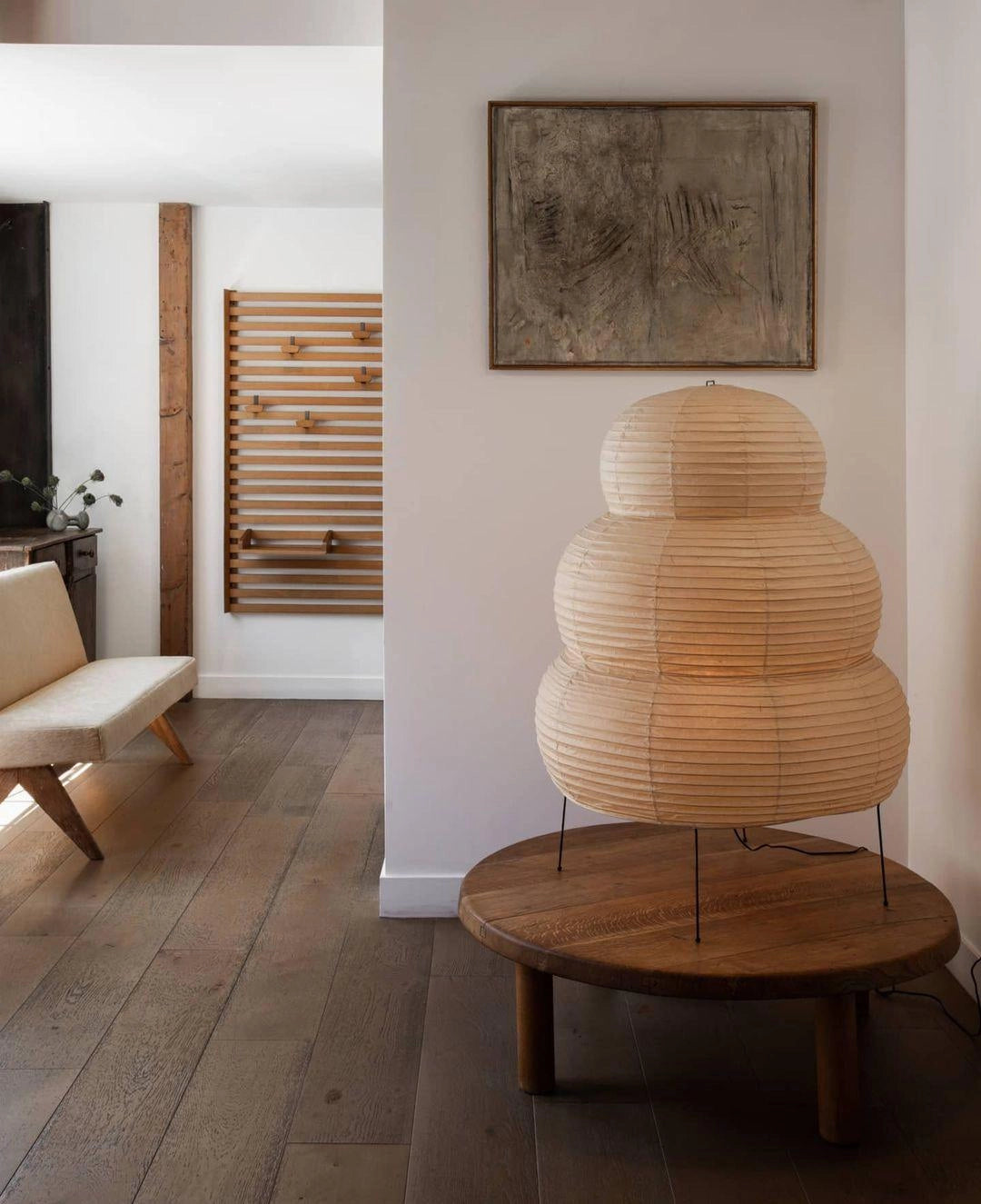 Unique sculptural tripod floor lamp with a beehive design, standing in a stylish interior setting with wooden flooring and modern decor.
