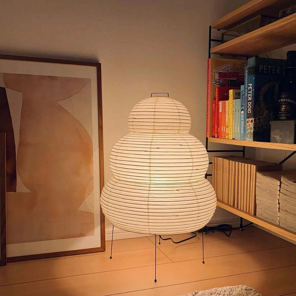 Beehive Sculptural Tripod Floor Lamp placed in a stylish living room with wooden shelving units and art pieces.