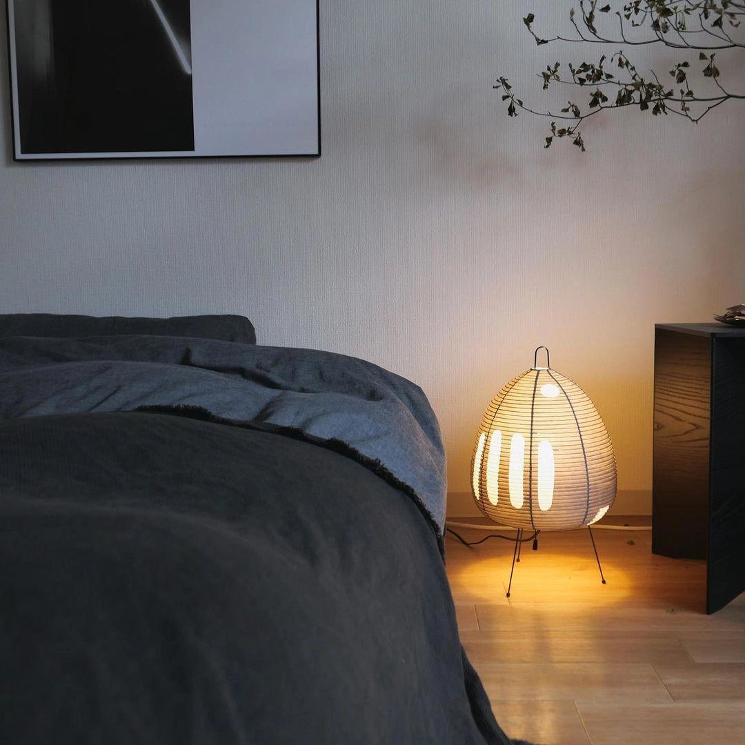 A unique beehive sculptural tripod floor lamp with a wooden base and textile shade, positioned in a modern interior design setting.