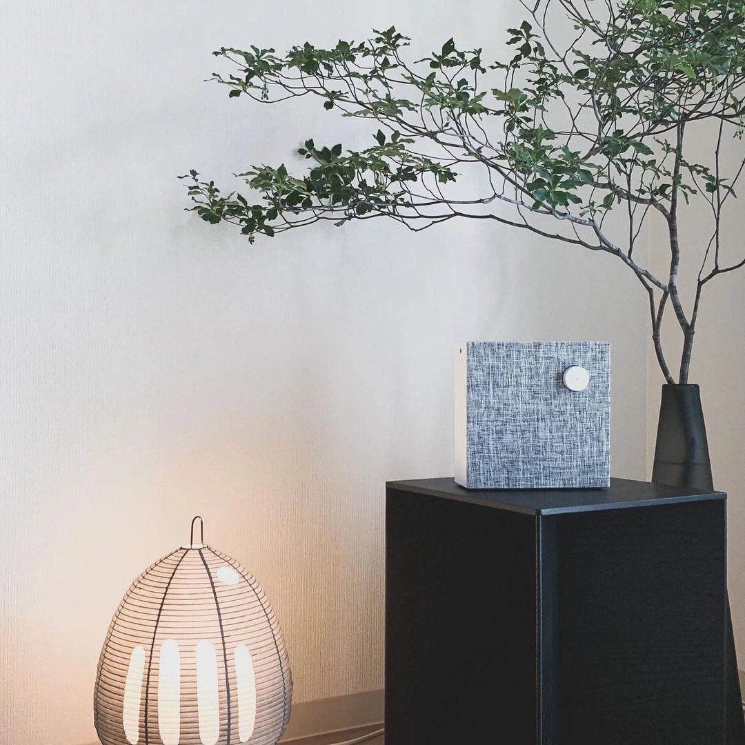 Beehive Sculptural Tripod Floor Lamp in a modern interior setting, featuring wooden tripod legs and unique beehive-shaped lighting, surrounded by plants and artistic decor.