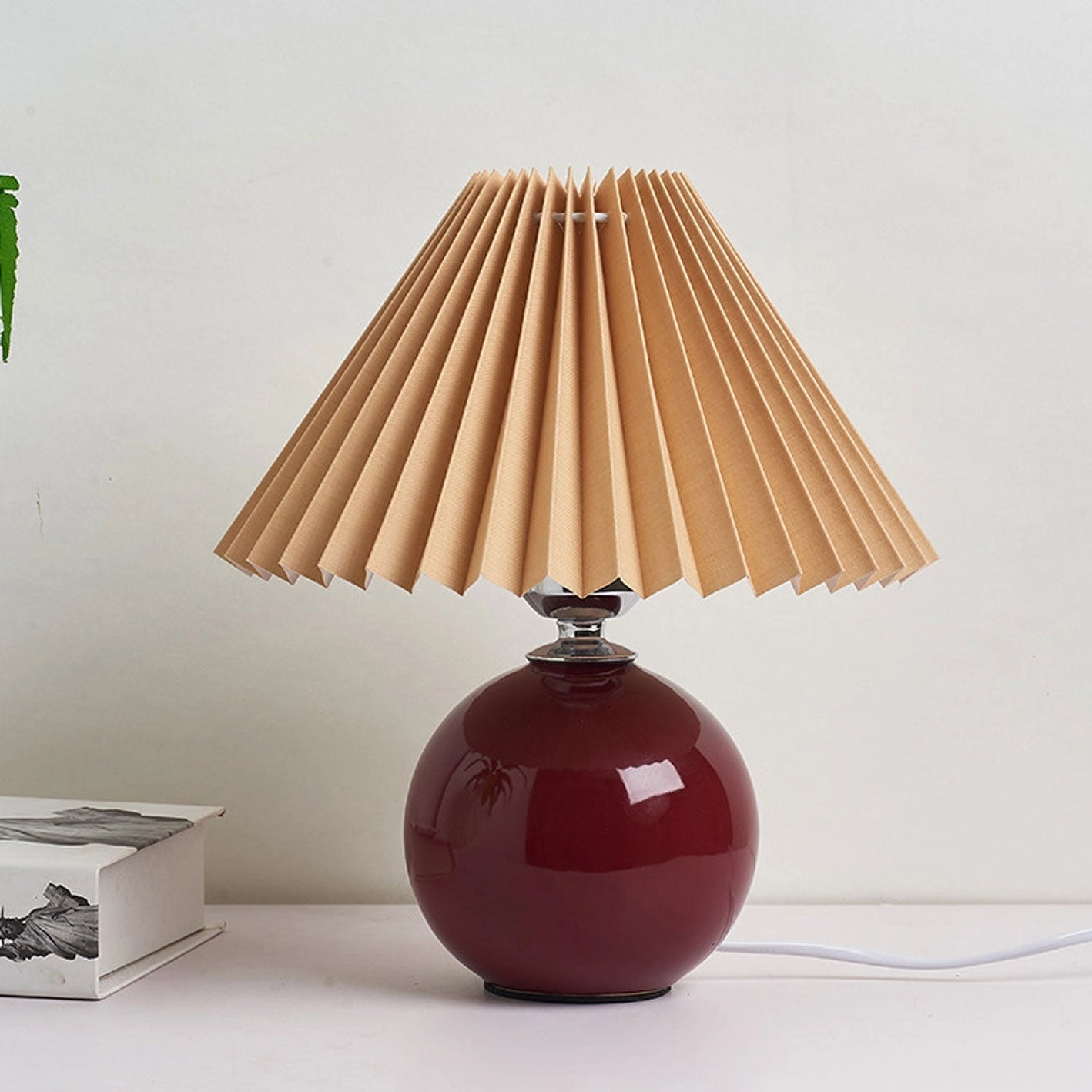Beige ceramic table lamp with an accordion pleated shade in burgundy and brown, featuring a pushbutton switch.