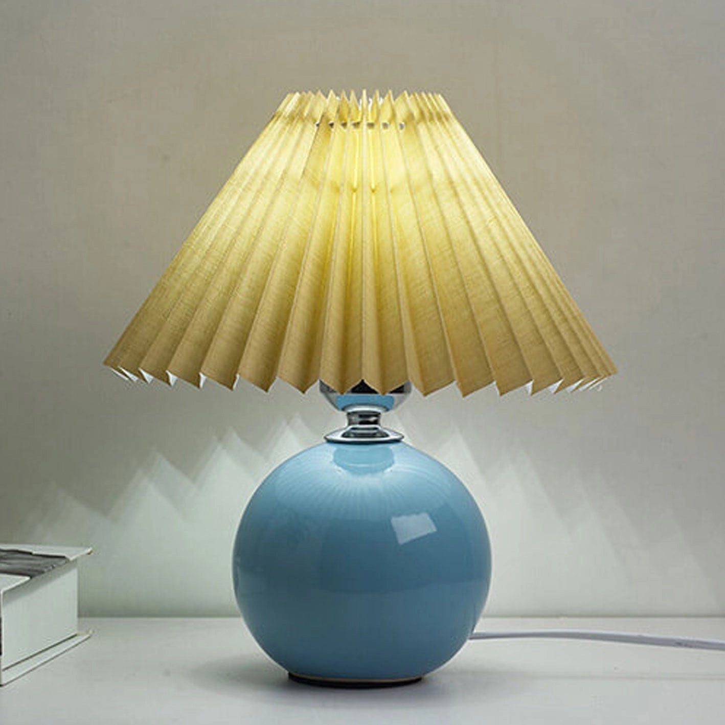 Beige ceramic table lamp featuring an accordion pleated shade, showcasing a stylish and elegant design ideal for adding a warm touch to any room.
