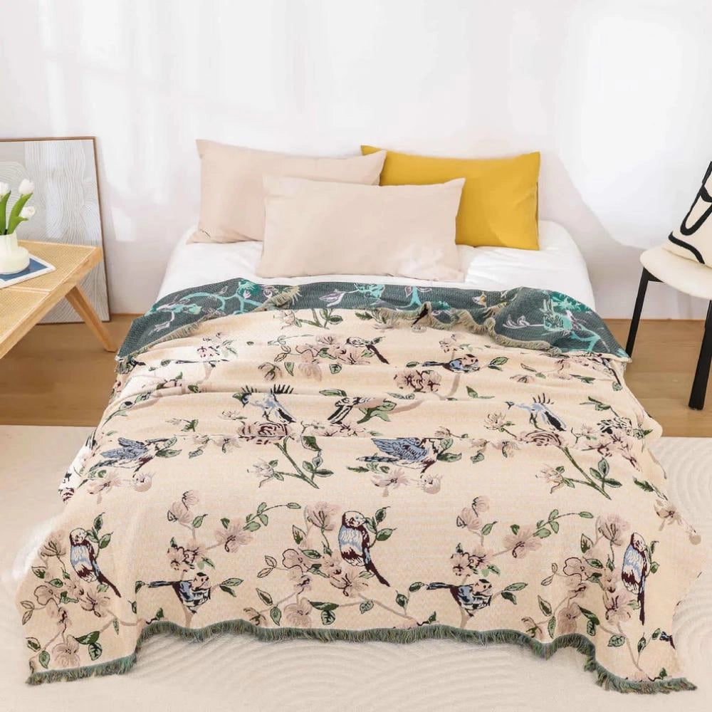Bird-themed floral quilt with botanical design on a neatly made bed, measuring 200x230cm, surrounded by wooden furniture and houseplants, creating a nature-inspired decor setting.