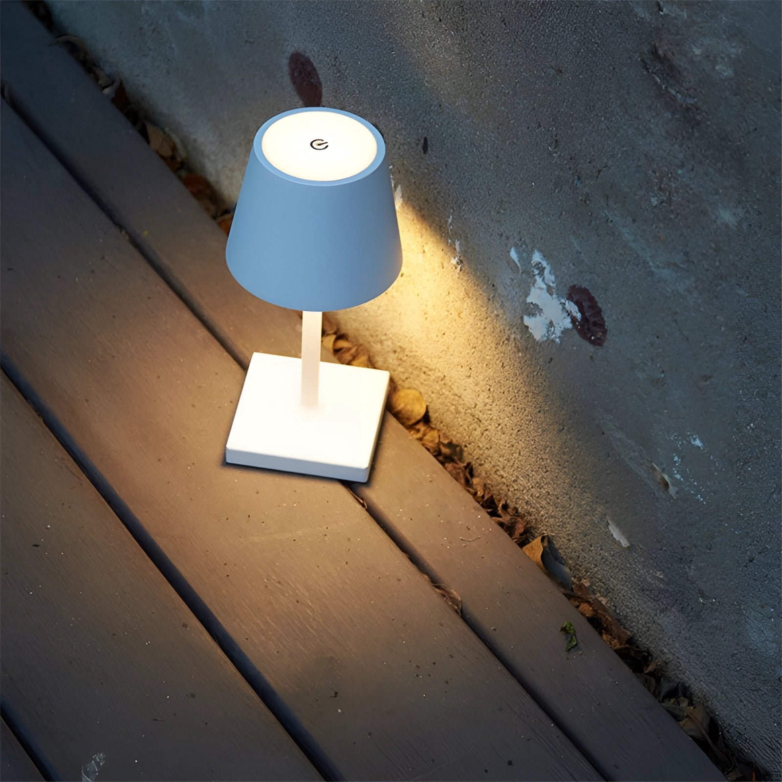 A sleek black LED desk lamp with a touch sensor and USB charging port, positioned on a wooden desk against a soft blue sky backdrop, showcasing adjustable brightness capabilities.