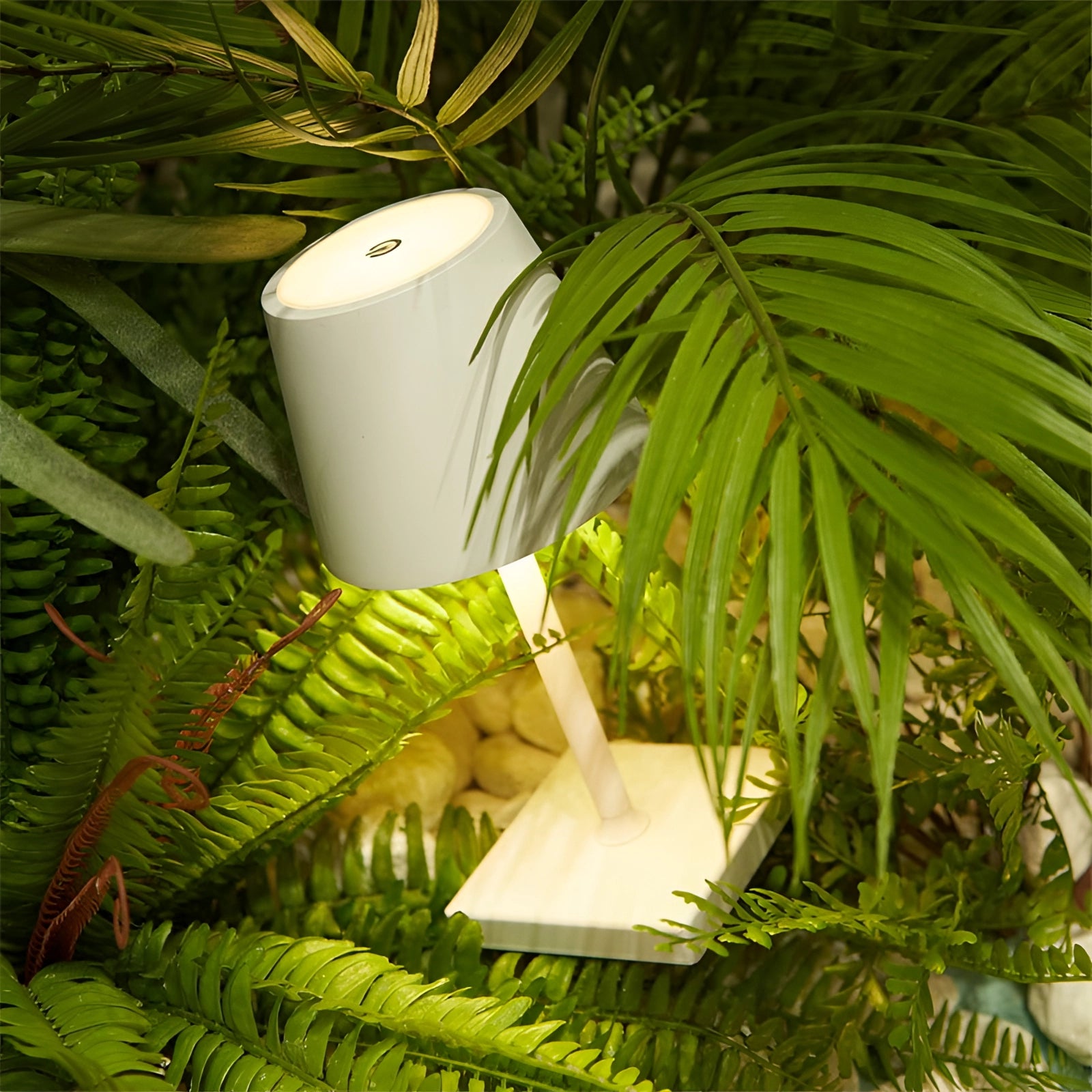 Black LED desk lamp with adjustable brightness, featuring a sleek modern design, situated on a desk with green leafy plants nearby.