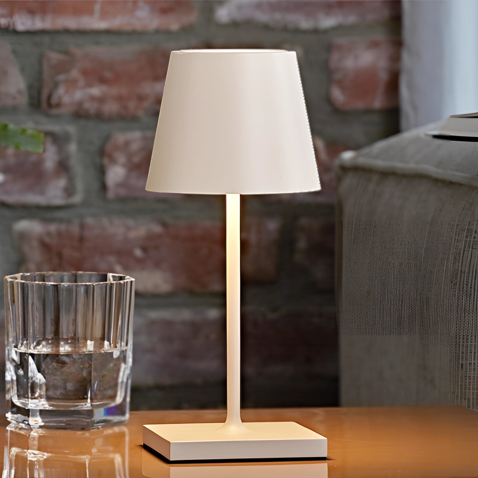White LED desk lamp with a rectangular base on a wooden table, featuring a touch sensor for adjustable brightness and USB charging capability, designed for modern interior settings.