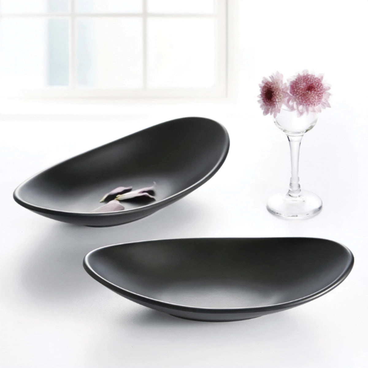 Black oval serving plates made from modern minimalist ceramic, displayed on a table.