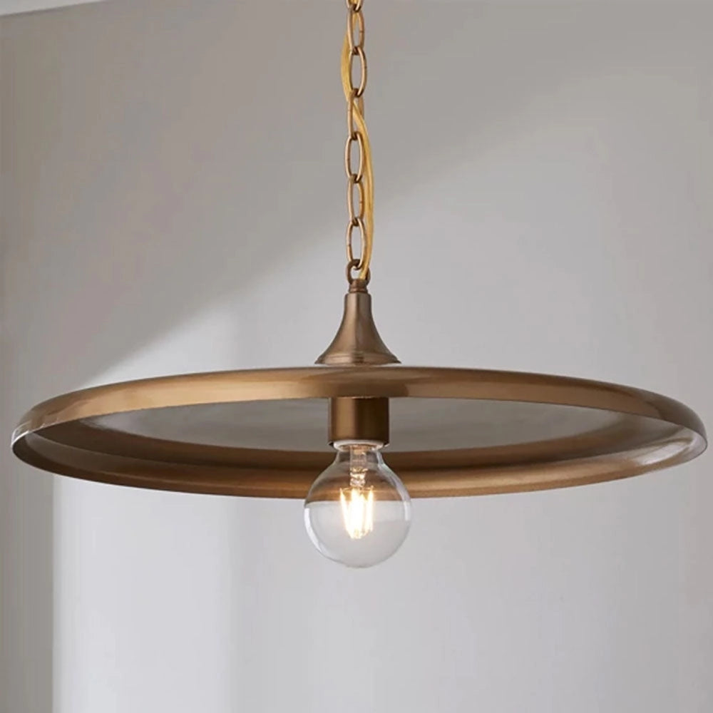 Bronze Minimalist Circular Metal Pendant Light with Adjustable Chain in Gold finish hanging above a wooden table, featuring a transparent glass shade.