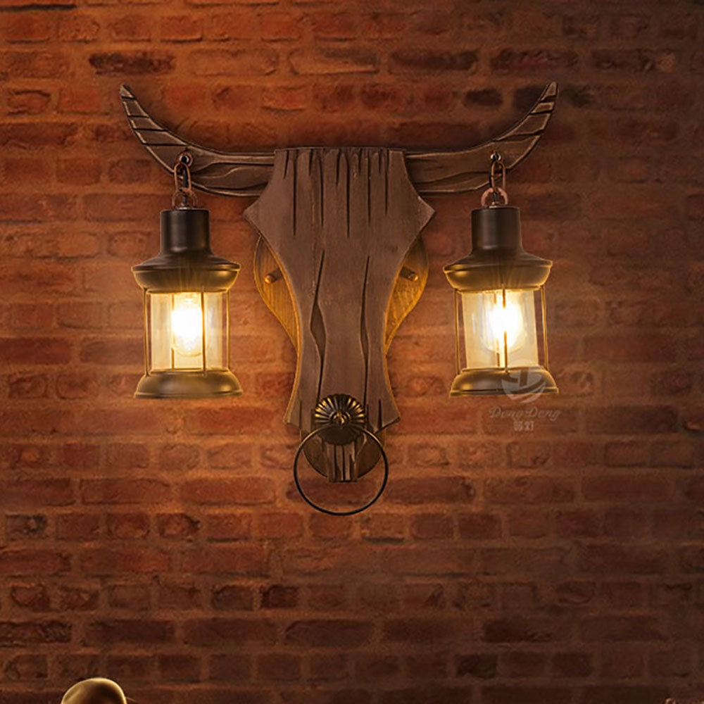 Brown Bull Head Dual Lantern with rustic amber glass shades, featuring a wood-like finish designed for outdoor wall installation.