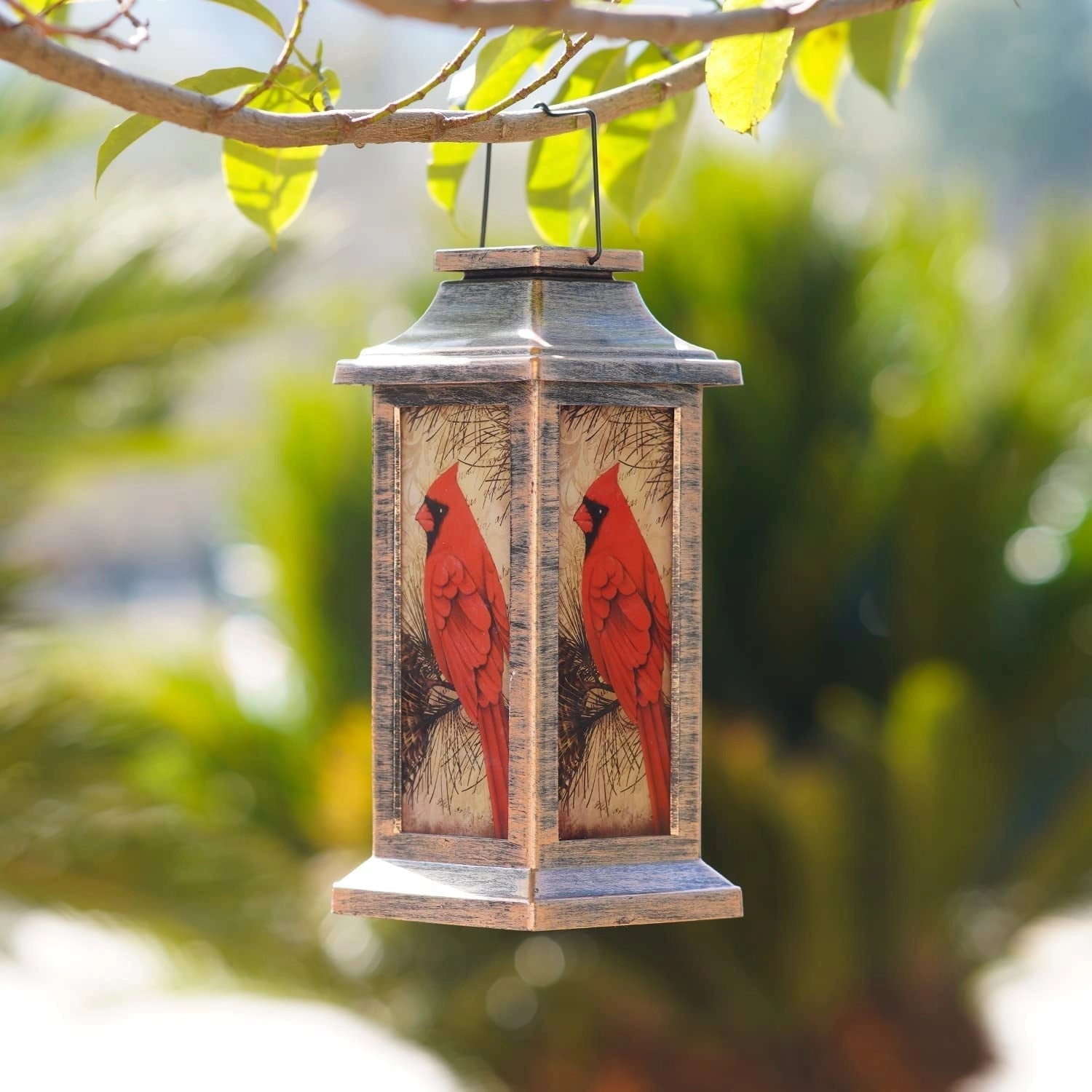 A rustic outdoor hanging lantern featuring a cardinal bird design, surrounded by twigs and wood elements, ideal for wildlife decor in gardens or patios.
