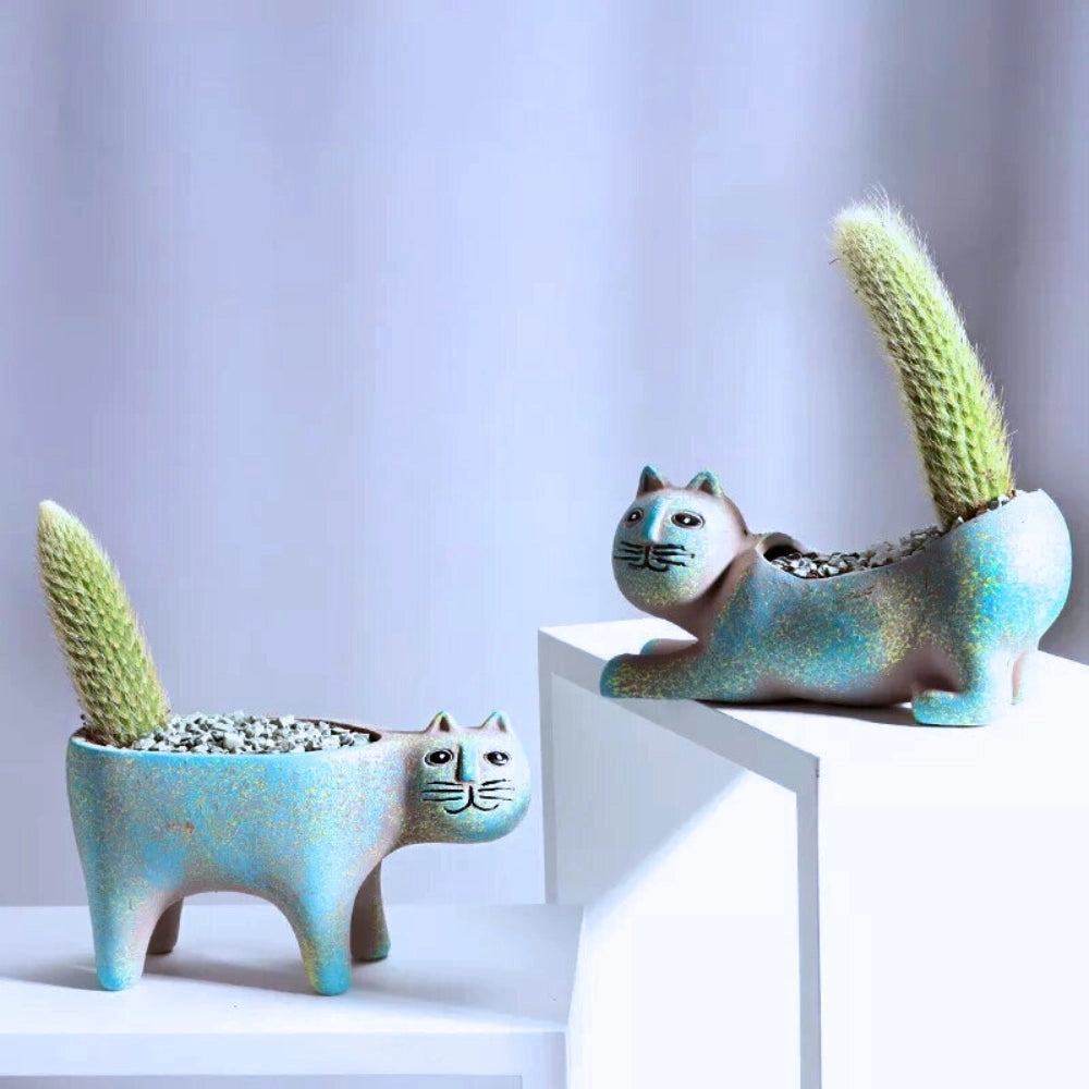 A blue ceramic cat-shaped planter displayed on a wooden shelf, featuring a whimsical design ideal for indoor decor.
