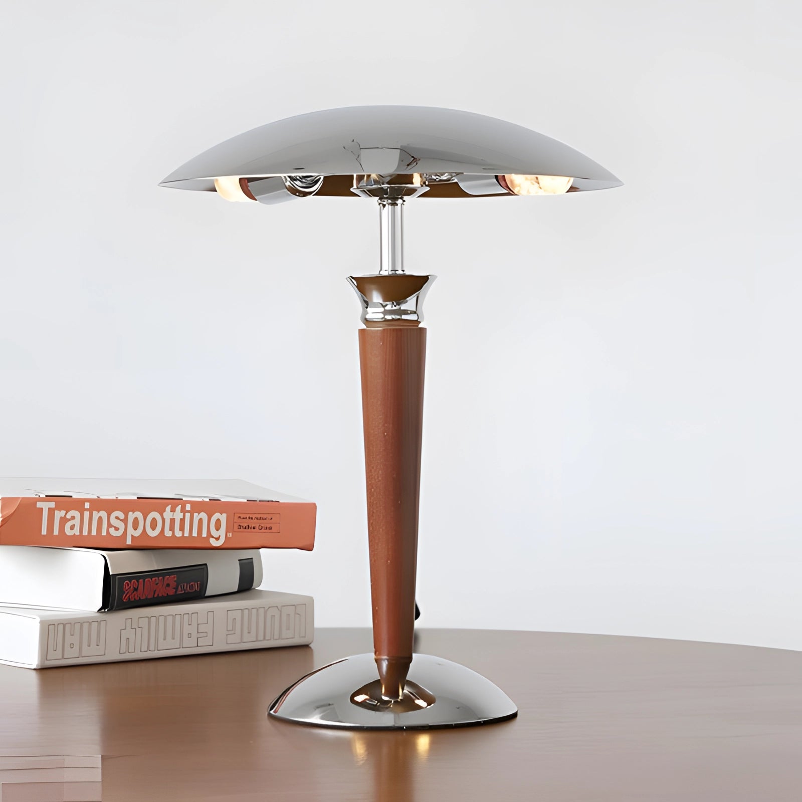 Chrome finish metal table lamp with adjustable dimmer, featuring a modern and elegant design; includes a sleek lampshade and a sturdy pedestal base, set against a backdrop of wooden flooring and decorative plants.