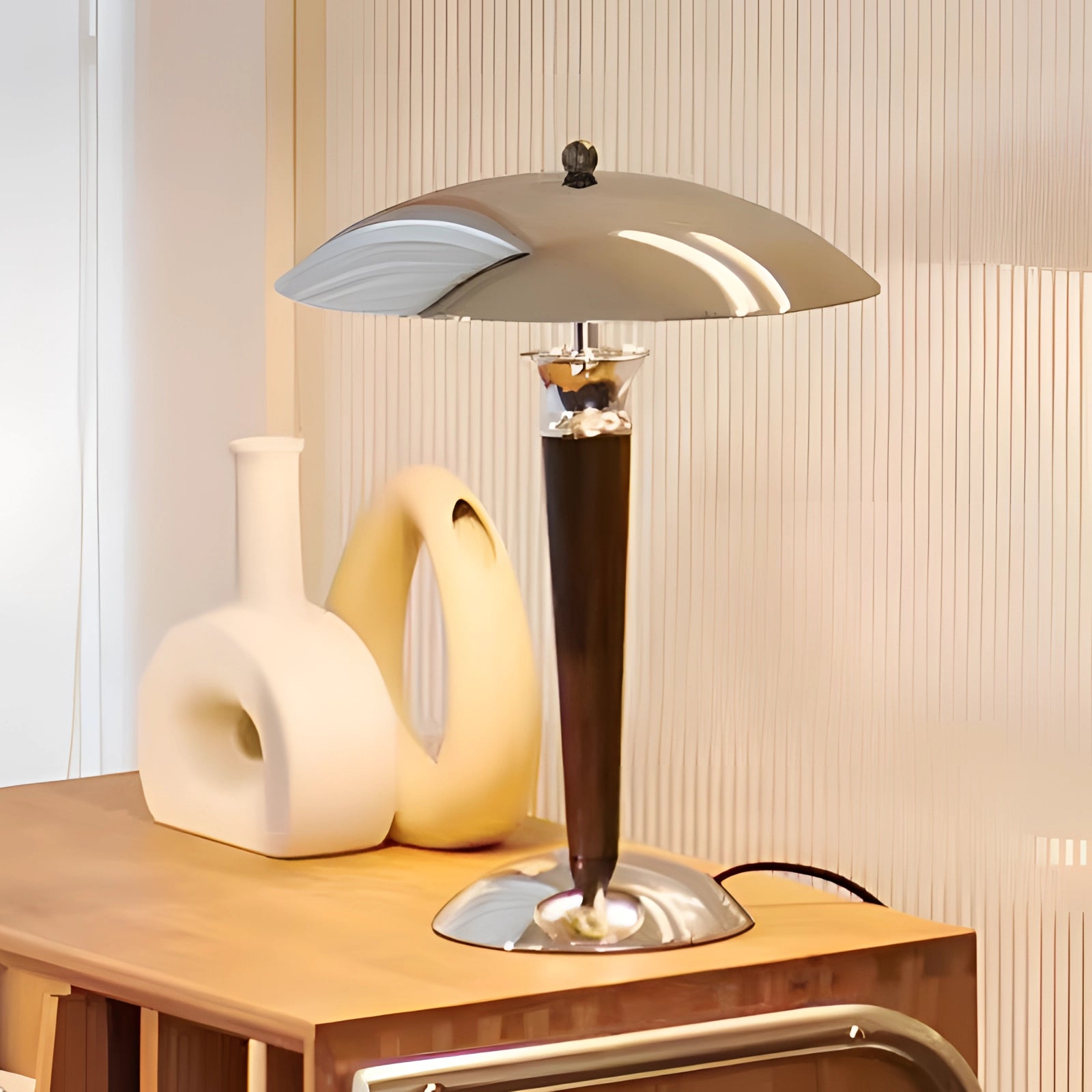 Chrome finish metal table lamp with adjustable dimmer, placed on a wooden table, showcasing its modern and elegant design in an interior setting.