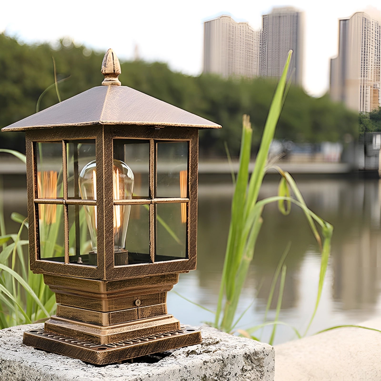 Classic vintage-style metal lantern hanging on a wooden gazebo outdoors near a lake, with trees and a clear sky in the background.