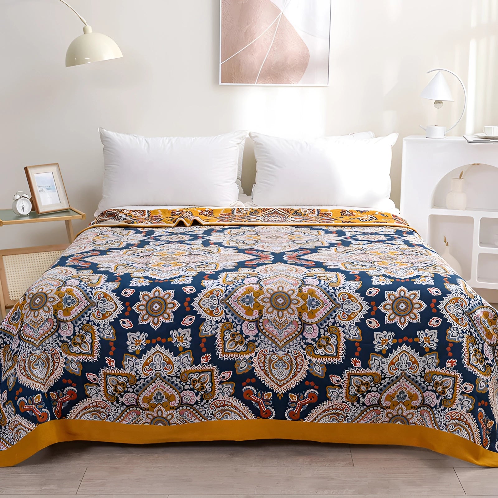 Colorful Bohemian bedspread with ethnic and paisley patterns draped over a bed, featuring vibrant azure tones. The bedding set is complemented by matching pillows, set in a cozy room with wooden flooring and large windows that allow natural light to enhance the interior design. The bedspread size is 200 x 230 cm.