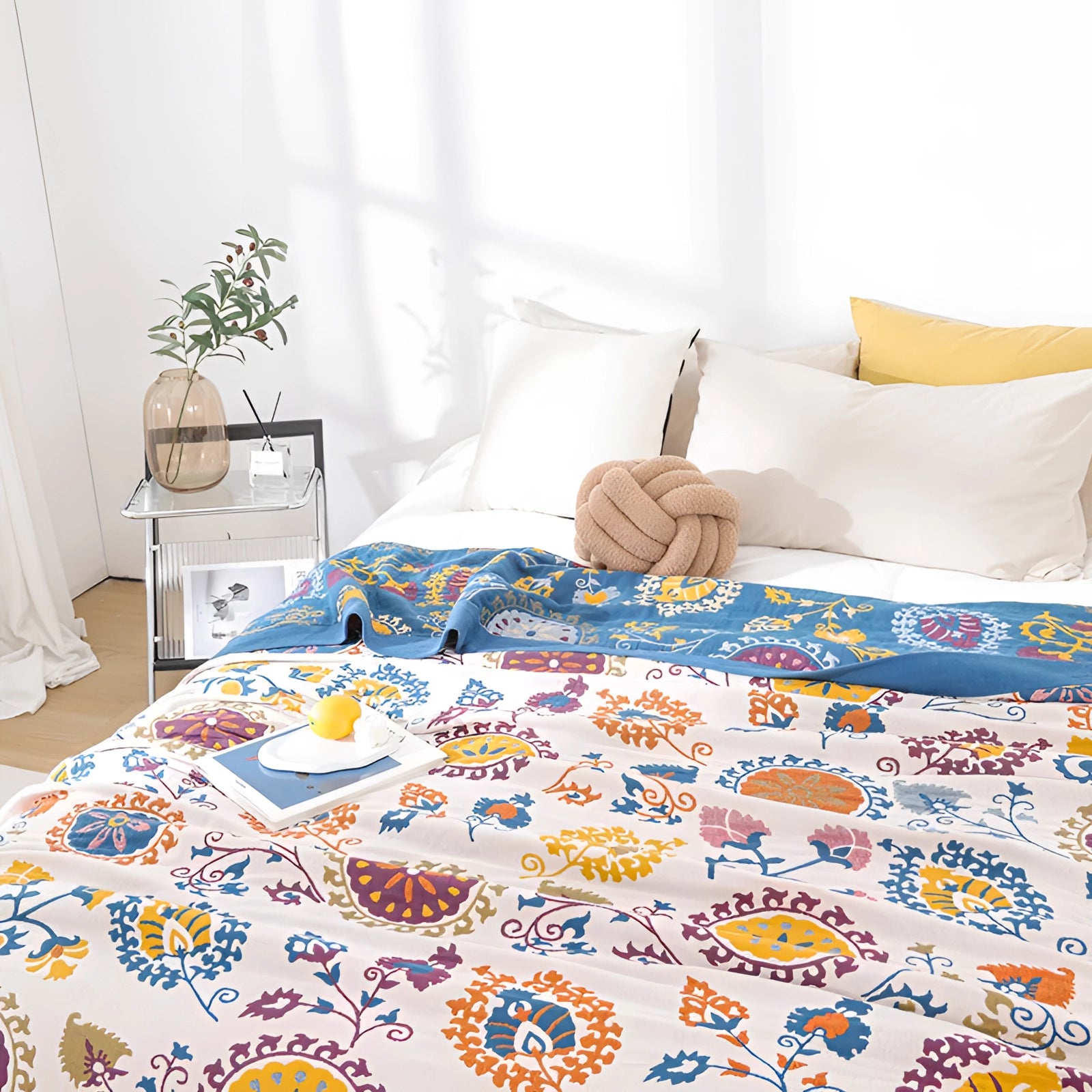 Colorful bohemian bedspread featuring an ethnic pattern with paisley design, draped over a bed in a tastefully decorated interior space.
