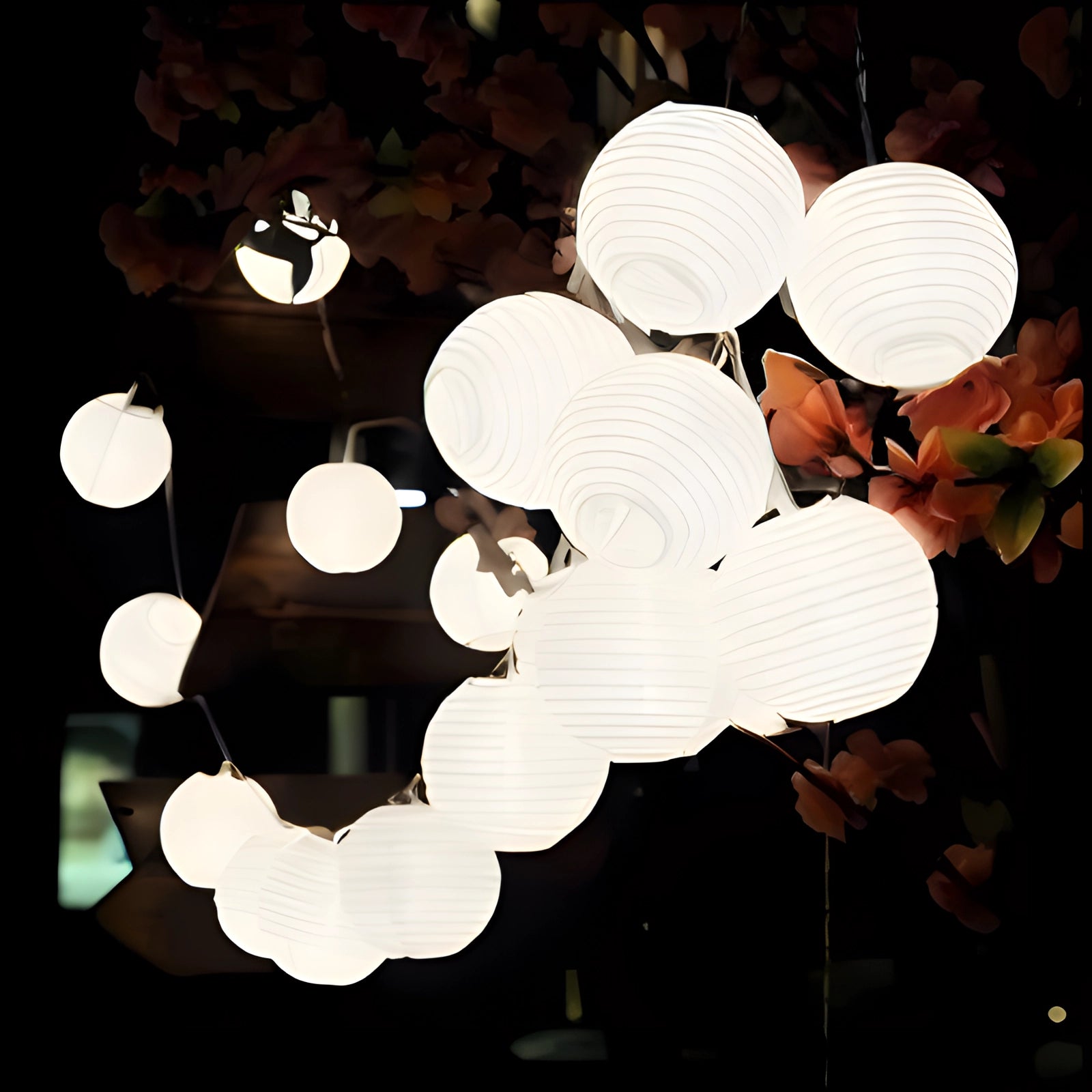 Colorful LED outdoor string lights with weatherproof multicolor lanterns displayed in a garden setting. The lights are arranged on a tree branch, showcasing the soft glow of the 30 white LEDs over a length of 6.5 meters. The background features a partially cloudy sky, creating an inviting and festive atmosphere.