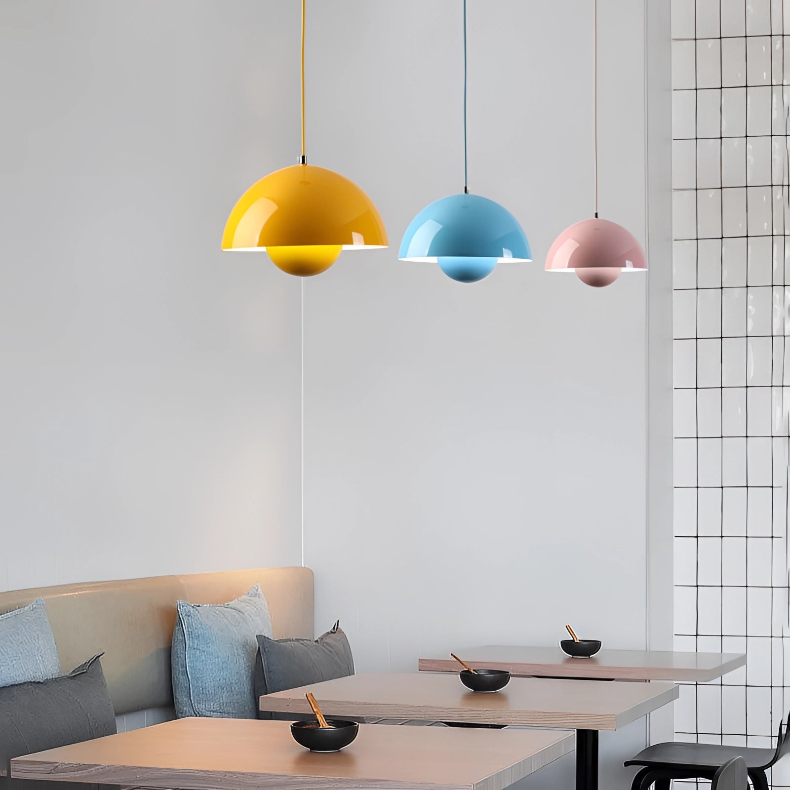 Modern dining room with colorful pendant lights, wooden table, white and yellow decor, Scandinavian design, art on walls, and shelving.