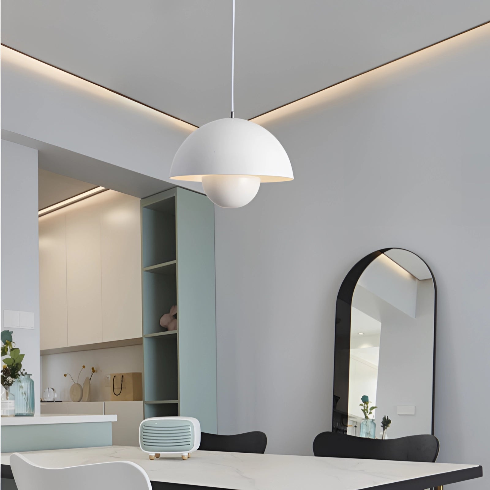 Colorful pendant lights hanging in a modern dining room with retro and Scandinavian decor, featuring a wooden floor, a large mirror, and indoor plants.