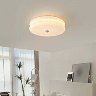 Cream ceiling lamp with a modern frosted glass design, illuminating a stylish interior space.