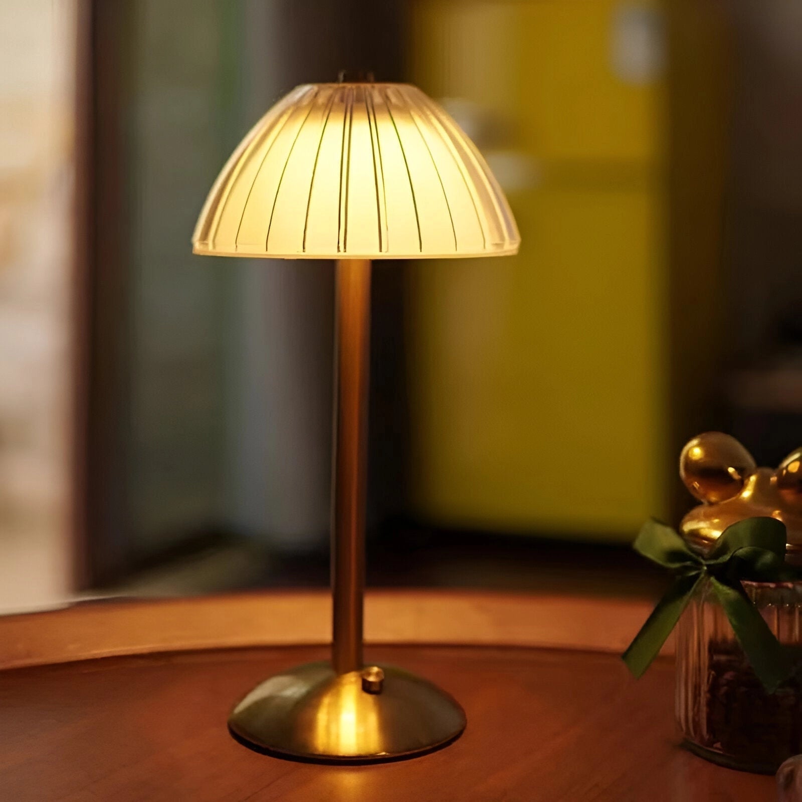 A modern wireless table lamp with a gold metal base and a geometric lampshade, featuring a blend of contemporary design and warm lighting.