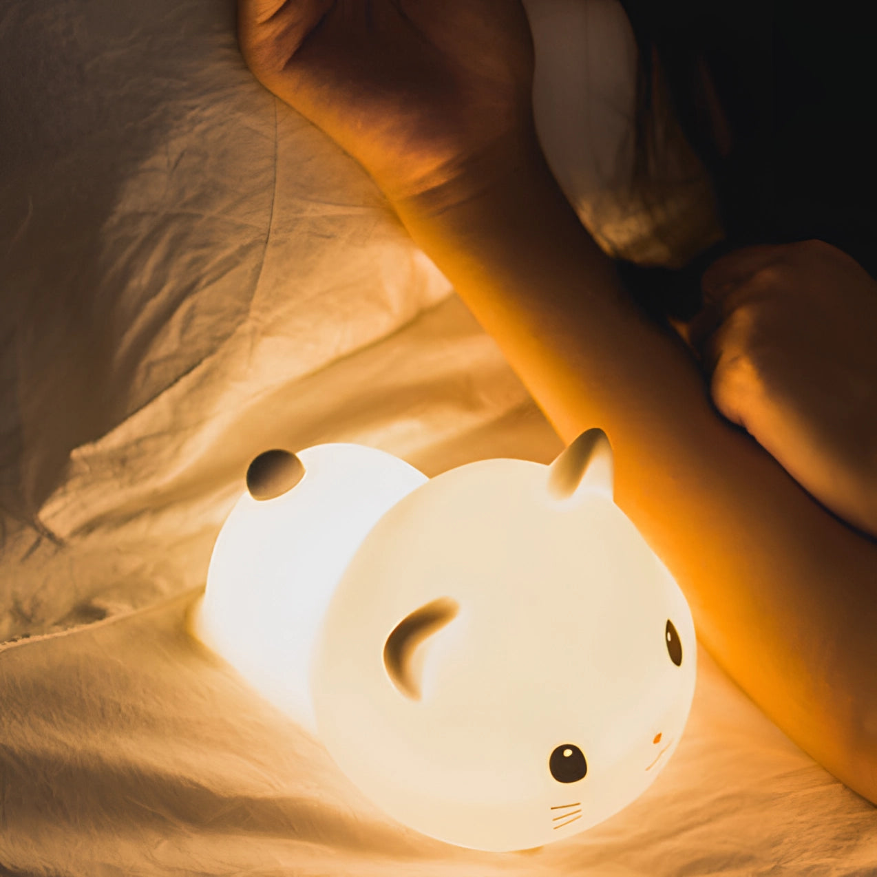 A close-up of a Cute Cat LED Nightlight shaped like a kitty, made from soft silicone, resting on a wooden surface. The lamp is designed to provide a comforting glow, perfect for children's bedrooms.