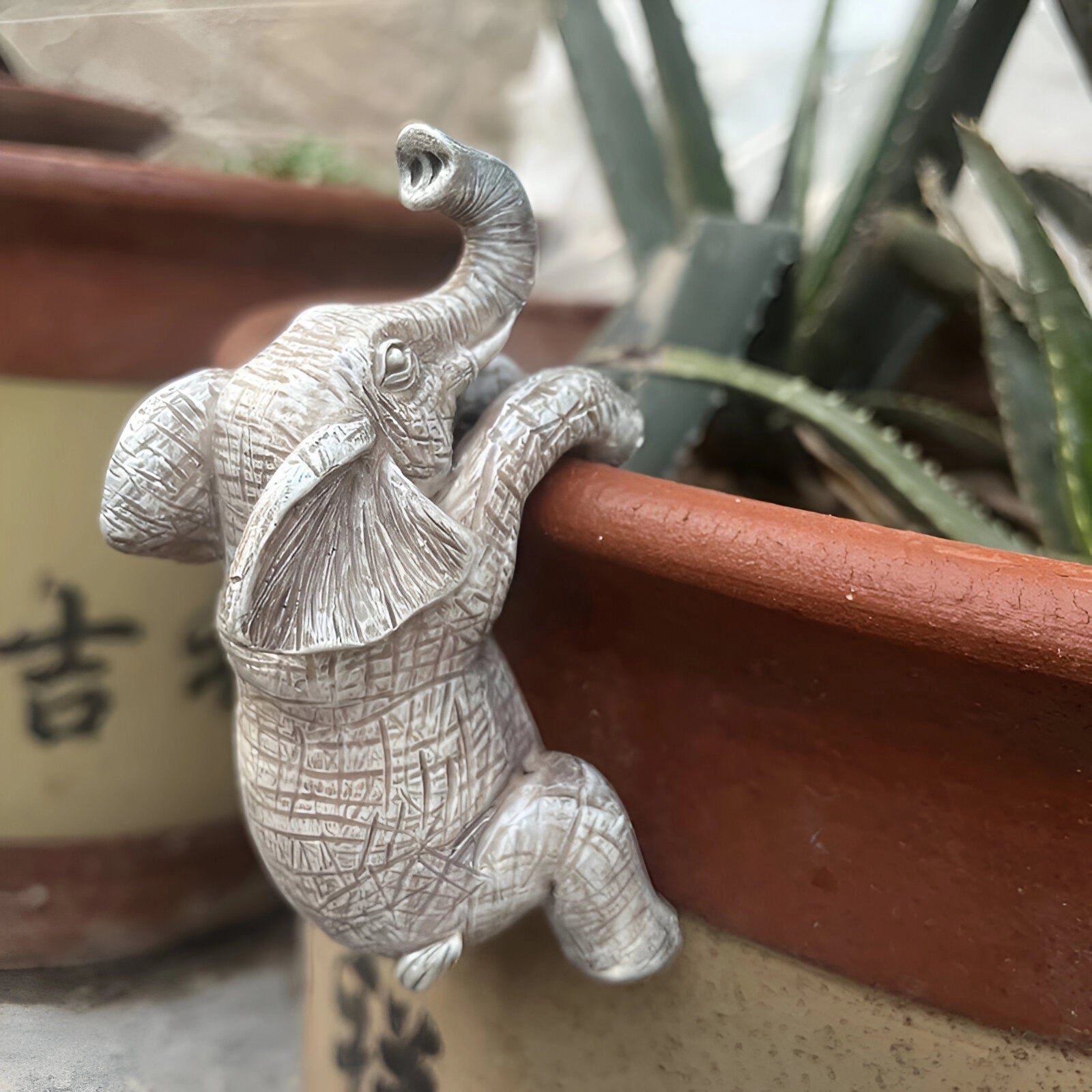 Decorative ceramic elephant planter pot featuring a boho wildlife design, with a close-up view showcasing the artistic details and vibrant terrestrial plant inside.