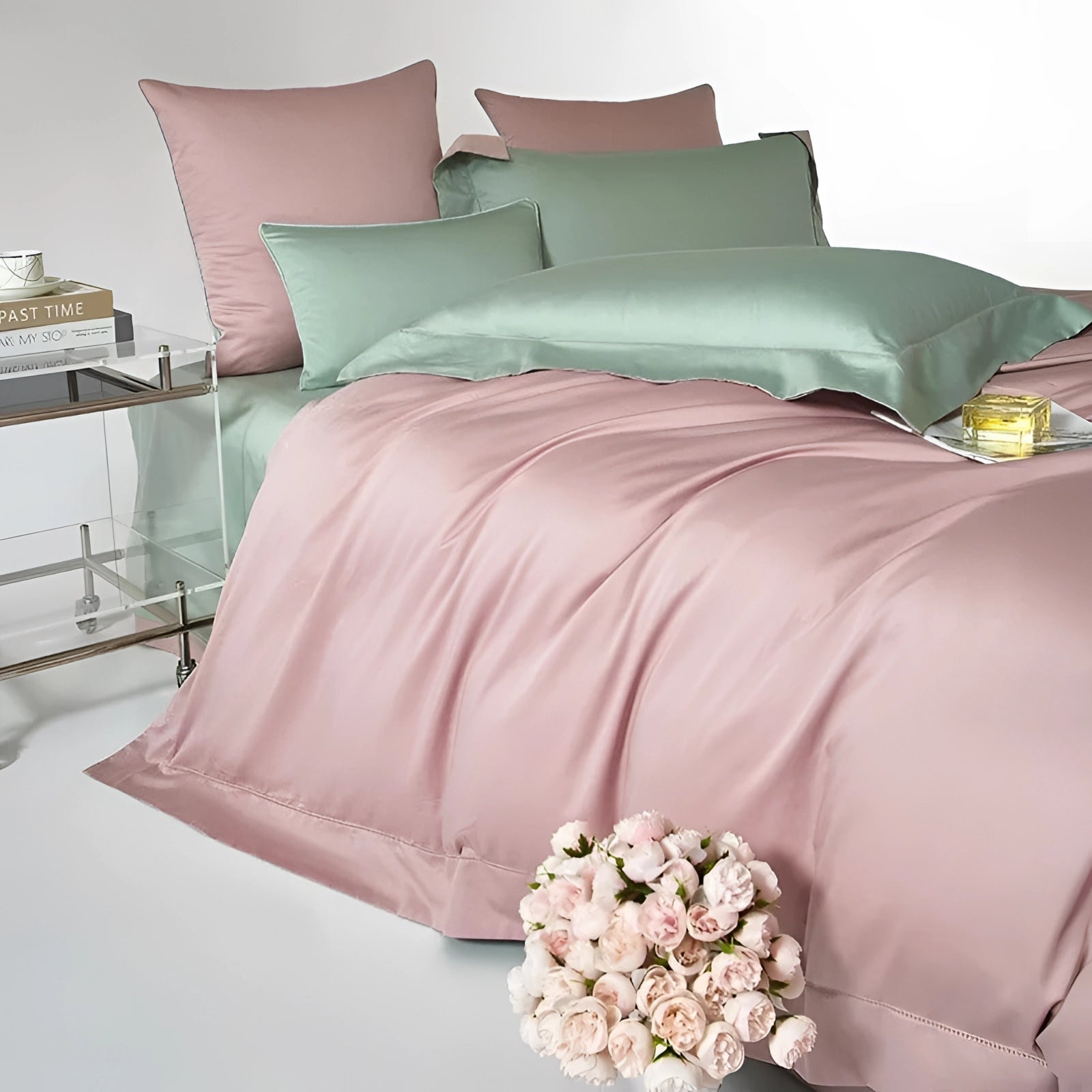 Dual-Color Egyptian Cotton Duvet Set in pink and green on a neatly made bed with white pillows, set against a grey bed frame on a wooden floor.