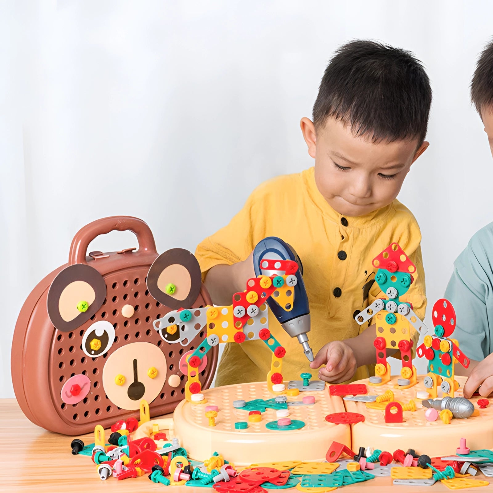Kids' electric drill toy set spread out on a table, surrounded by colorful cake decorations, indicating a birthday party celebration setting.