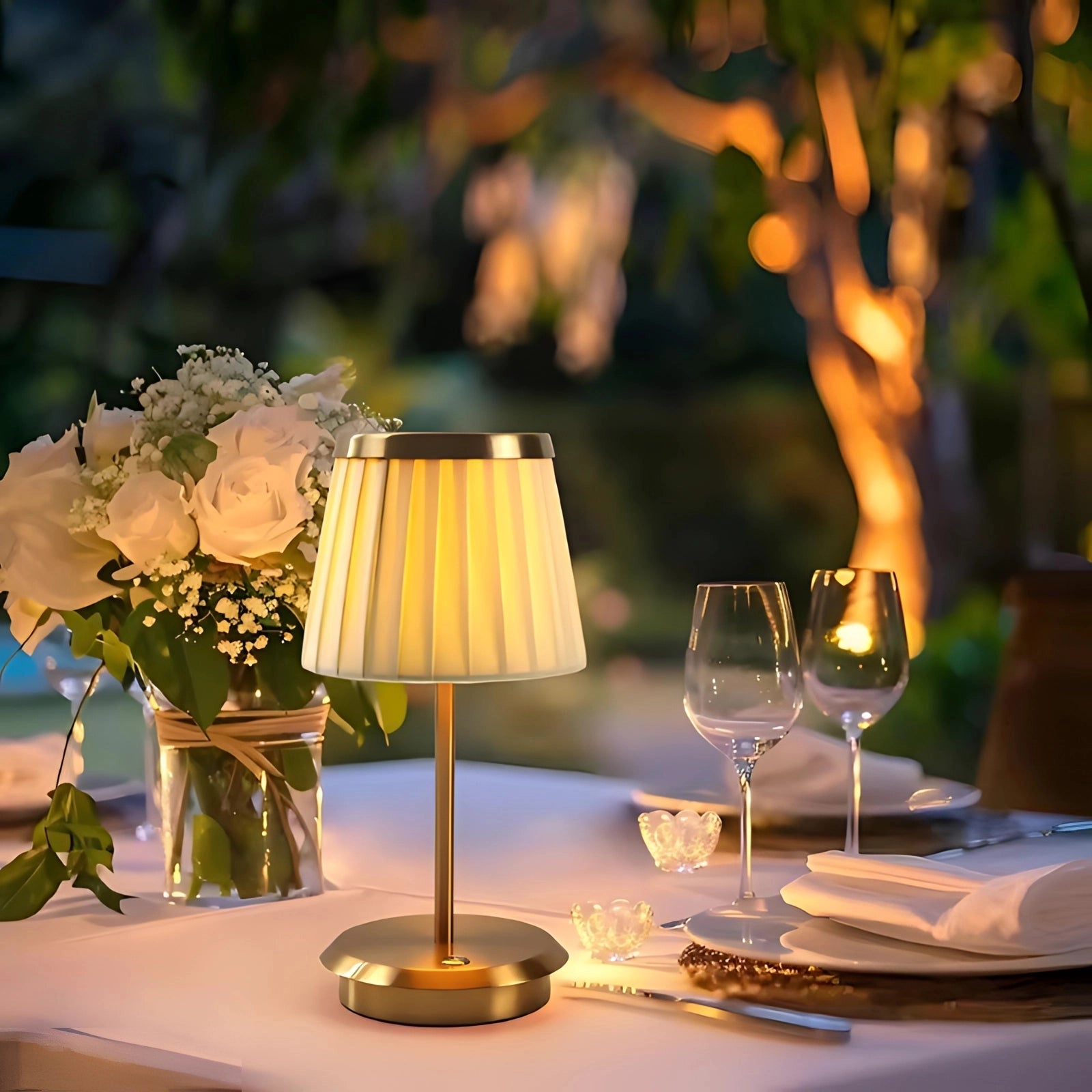 Elegant Cordless LED Outdoor Lamp placed on a table surrounded by decorative elements such as wine glasses, plants, and flowers, emphasizing its use as stylish and functional outdoor lighting.