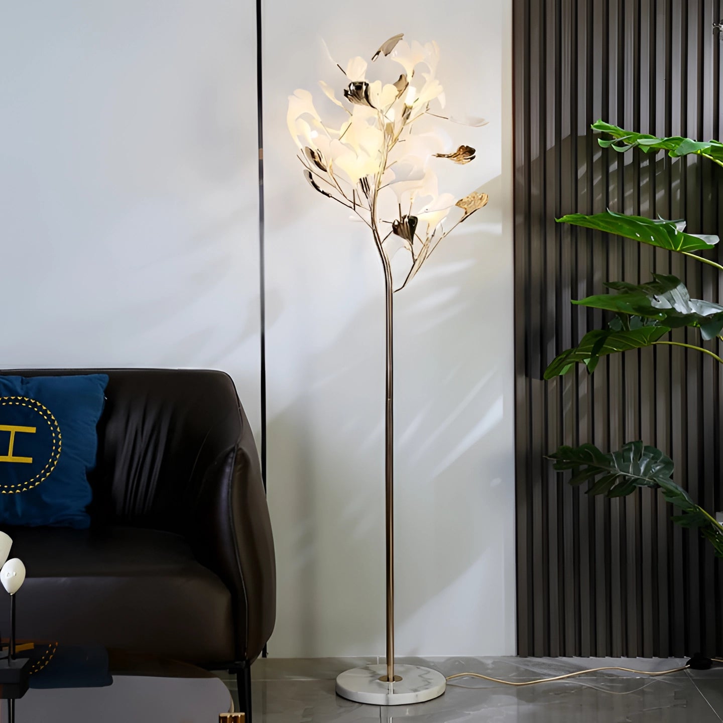 Elegant gold floor lamp with gingko leaf design, brass finish, nature-inspired, standing in a cozy interior setting.