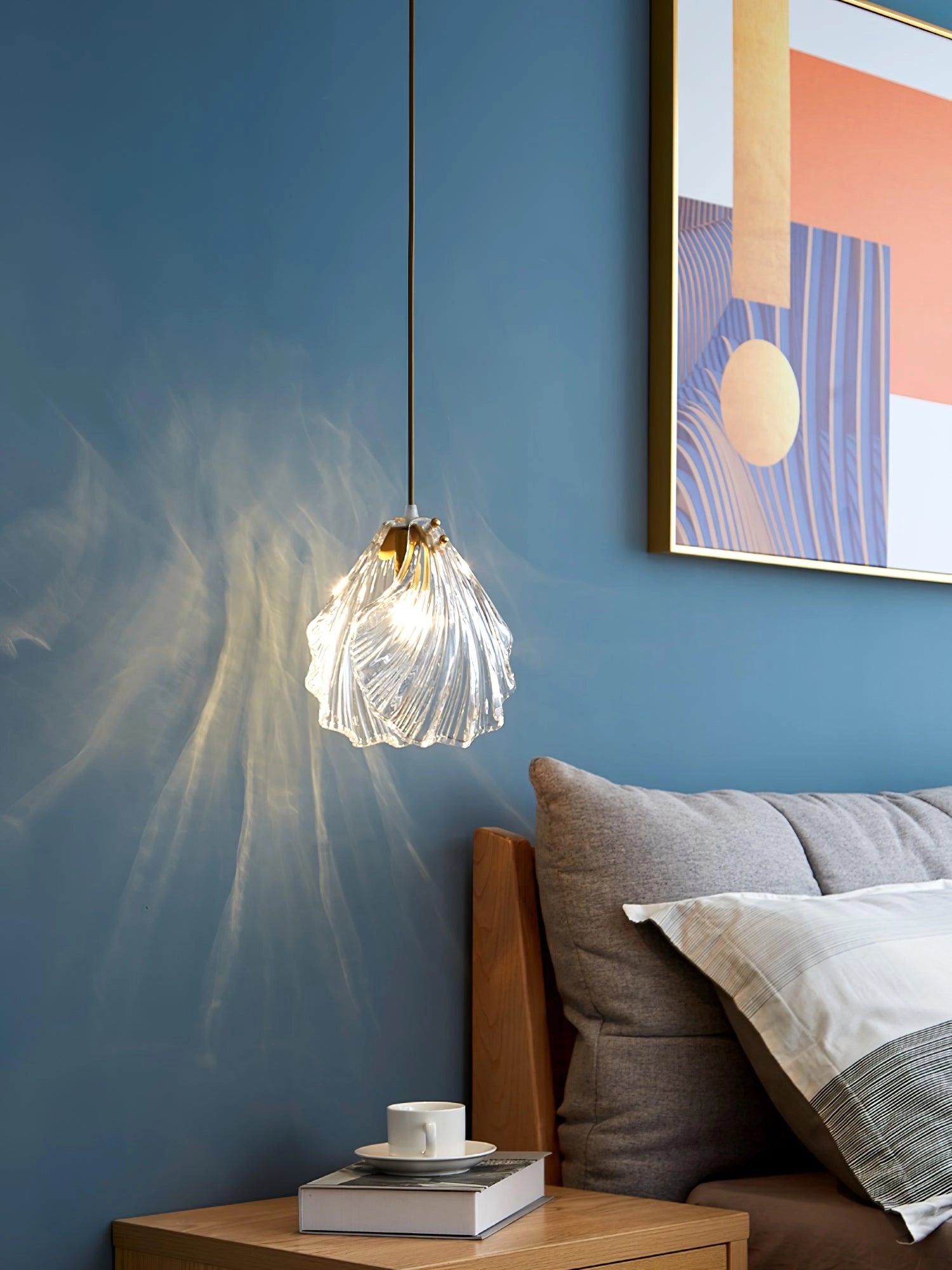 Elegant Petal Glass Pendant Light with modern LED floral design hanging in a stylishly decorated room with large windows, wooden elements, and blue accents.