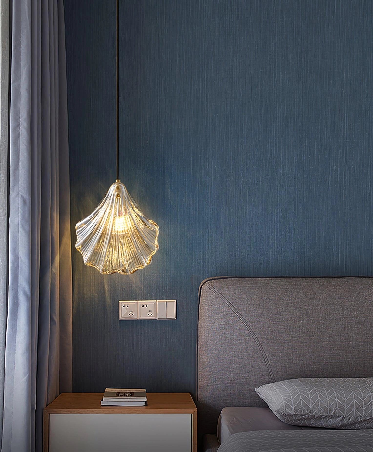 Elegant petal glass pendant light with modern LED floral design hanging above a cozy wooden-floored living room, featuring a comfortable couch, large window, and contemporary decor.