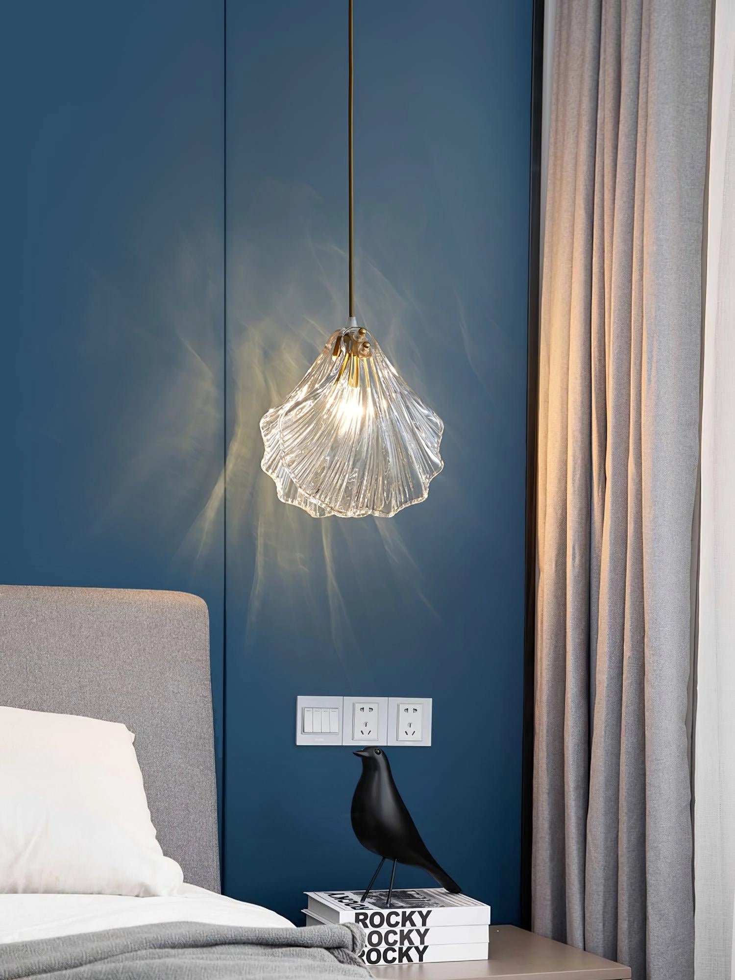 Modern LED floral chandelier with elegant petal glass design, hanging in a cozy room with wooden accents and large windows with azure curtains.