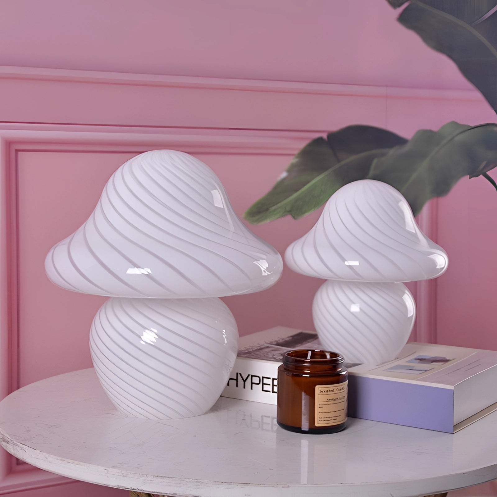 Elegant white spiral table lamp with a modern sculptural design, placed on a wooden table surrounded by houseplants and decorative objects.