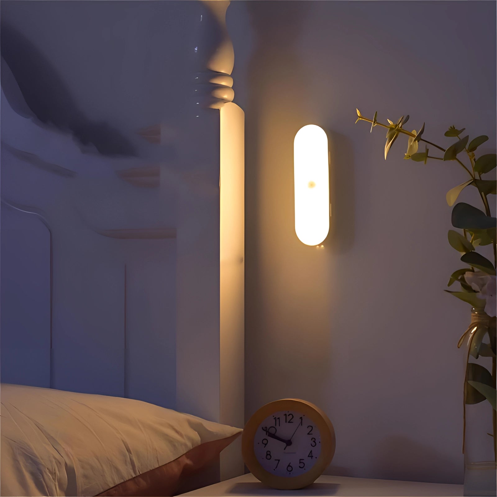 Energy-efficient adjustable LED reading light with motion sensor, positioned on a wooden surface in a comfortable interior setting alongside a plant in a flowerpot and a clock, showcasing modern lighting design.