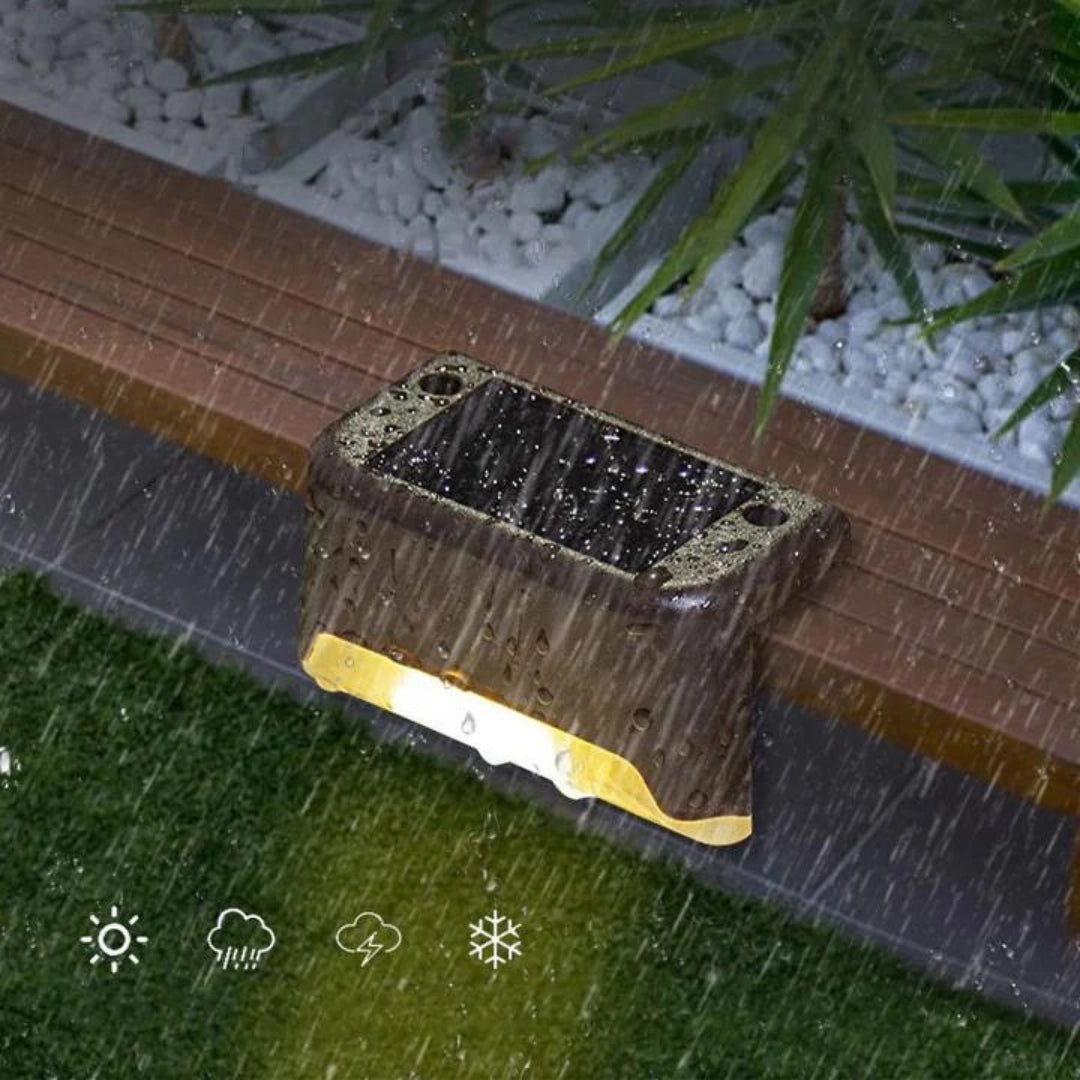Outdoor energy-efficient LED waterproof deck lights installed on a wooden patio floor surrounded by grass and plants, showcasing a rectangular hardwood design with a natural wood stain pattern.