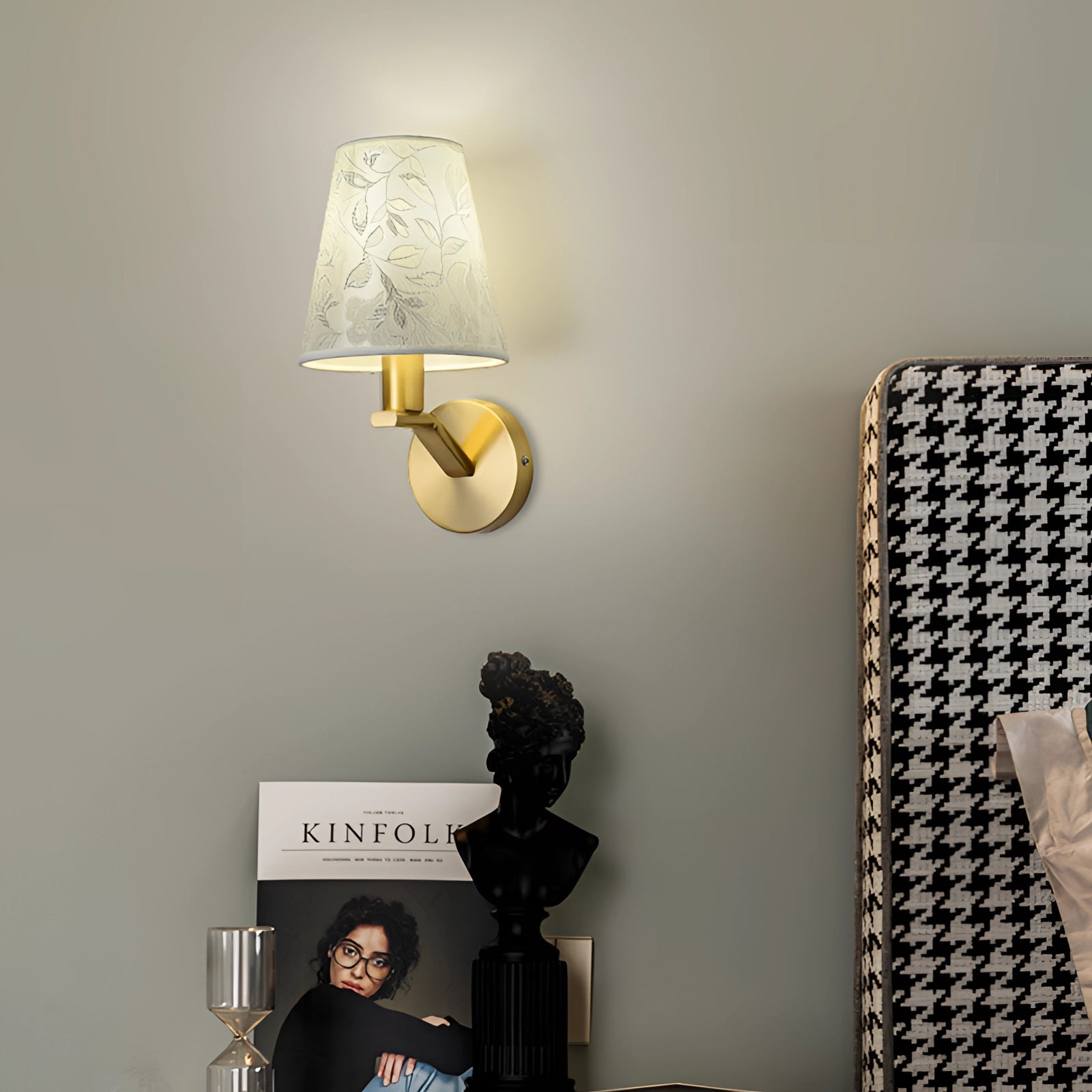 Floral pattern wall sconce with gold accents, featuring a rectangular shape and a lampshade. The elegant bedroom lamp is mounted on a wooden surface with a grey and metal finish.