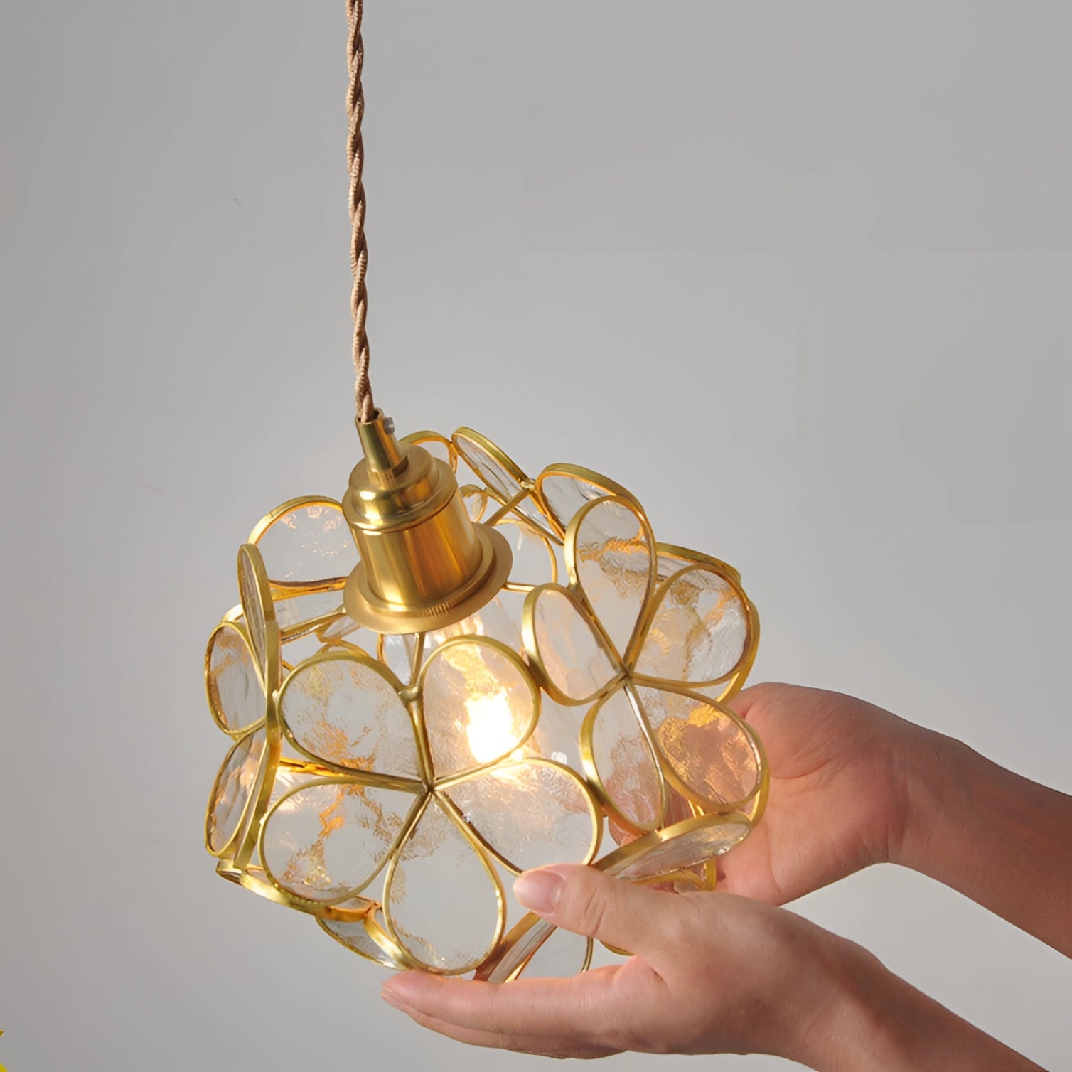 Modern floral pendant light with blossom design, warm amber and gold hues, circular shape, natural wood material accents.