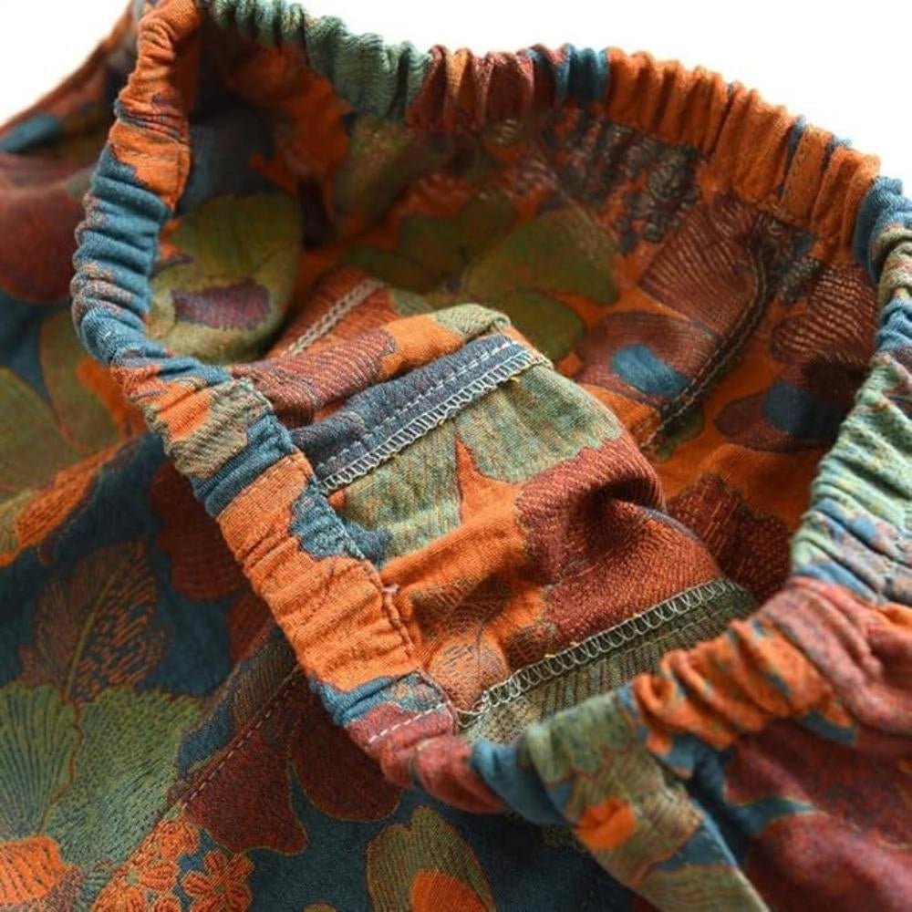 A pair of floral print pants featuring a ginkgo leaf design with an elastic waistband, showcasing an intricate pattern in warm brown and orange tones.