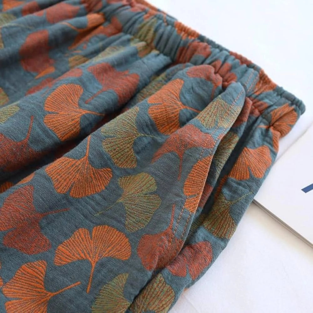Floral print pants featuring a ginkgo leaf pattern in shades of orange and grey with an elastic waistband.
