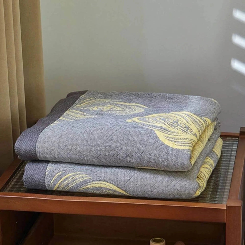 Floral Yellow Leaf Pattern Reversible Blanket in grey, displayed on a hardwood floor, showcasing its intricate pattern and soft, comfortable fabric.