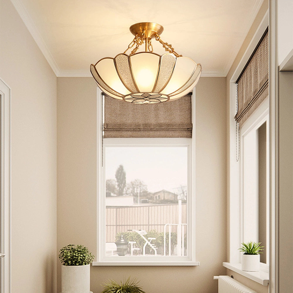 Gold Art Deco semi-flush ceiling light with frosted glass in an interior setting, surrounded by houseplants and windows, contributing to a stylish and elegant home decor.