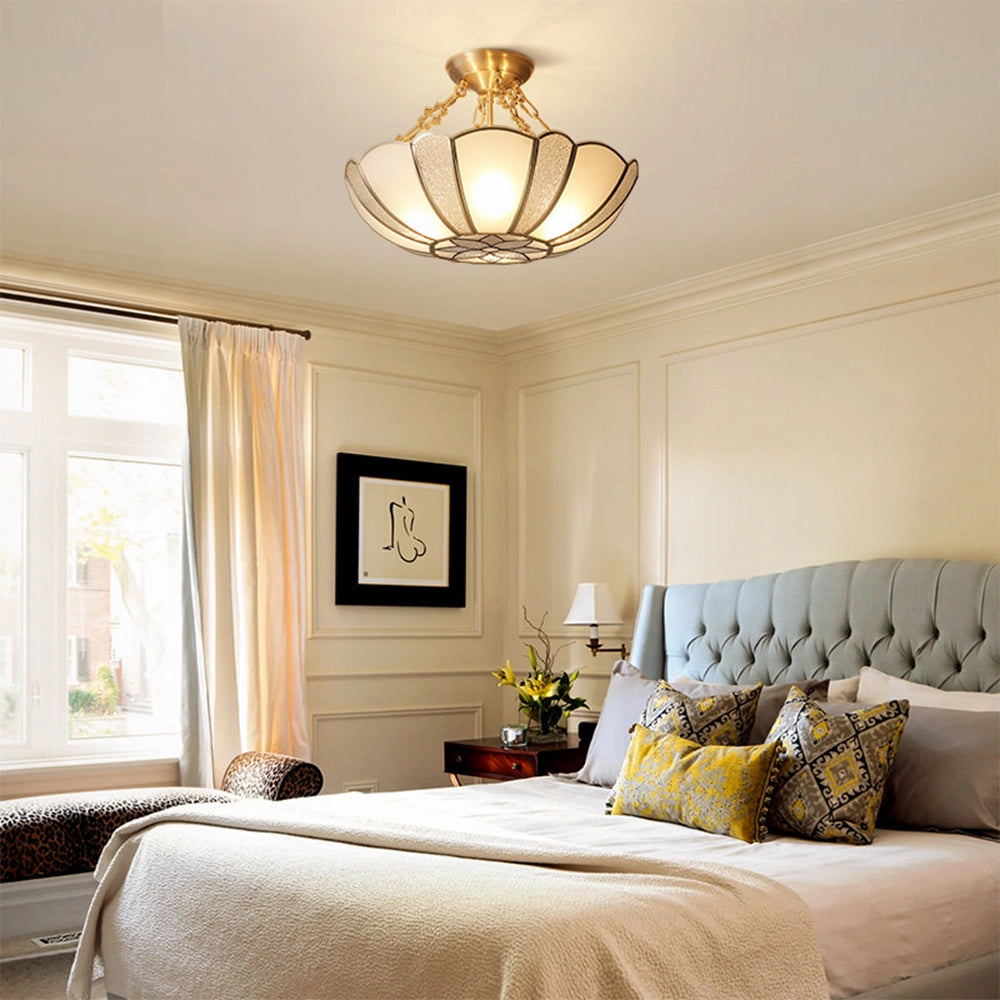 Gold Art Deco semi-flush ceiling light with frosted glass shade, installed in a stylishly decorated interior room featuring wooden flooring and large windows.