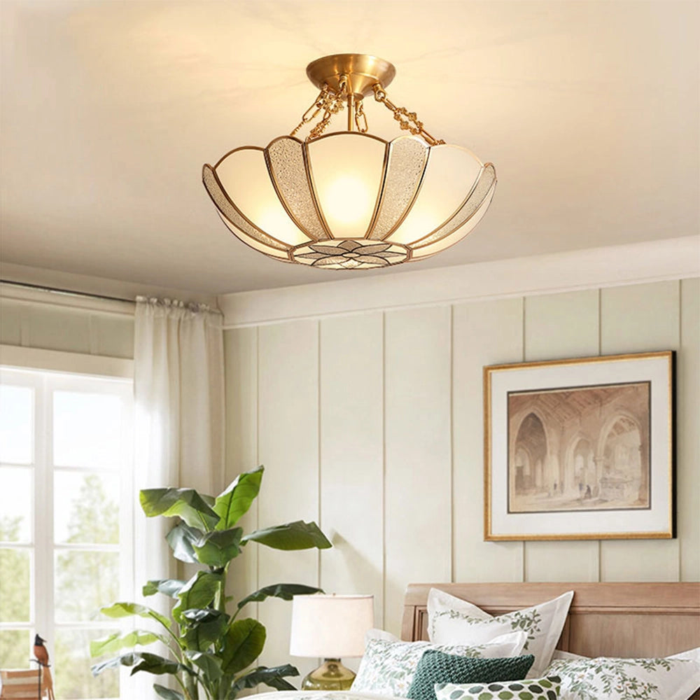 Gold Art Deco semi-flush ceiling light with frosted glass, illuminated in a stylish interior setting featuring a wooden floor, houseplants, and a large window.