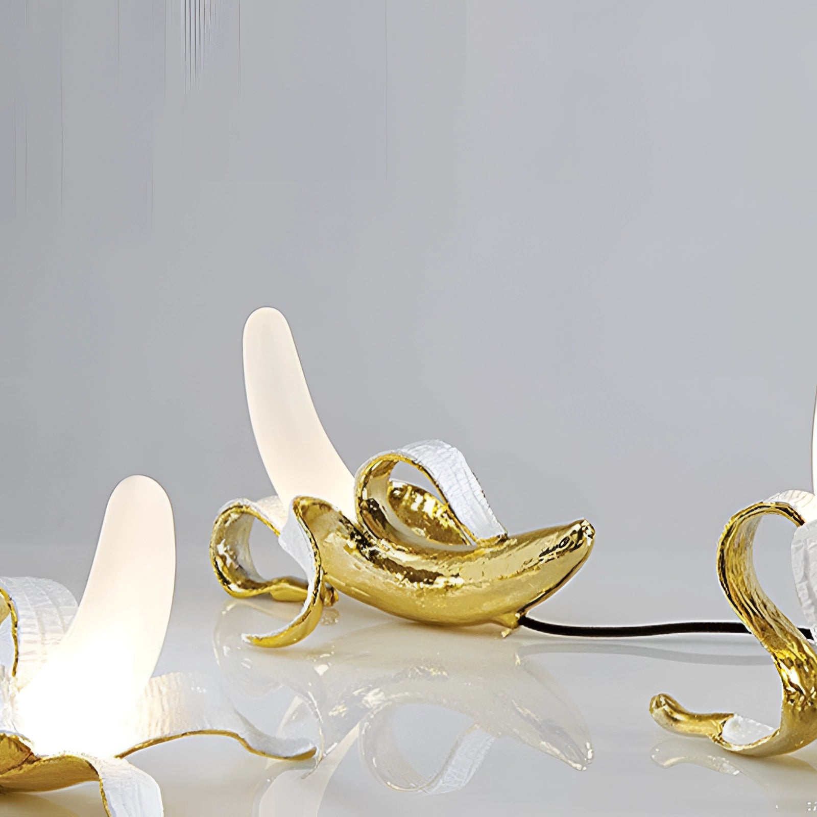 Gold banana-shaped resin table lamp designed as a modern art fruit sculpture, featuring a metallic gold finish, suitable for decorative purposes.