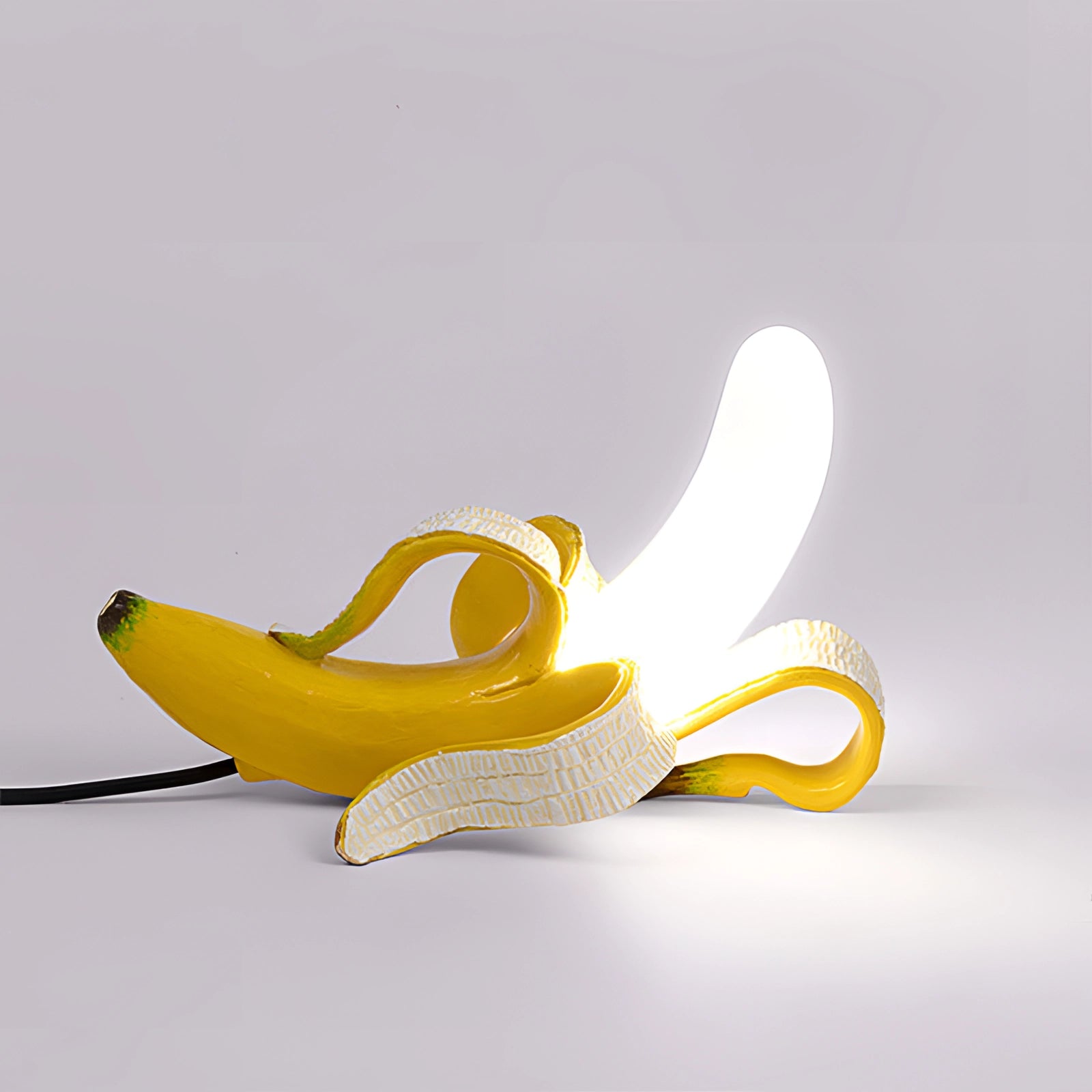 Gold banana-shaped resin table lamp with modern art fruit sculpture design in yellow, featuring a unique artistic style.