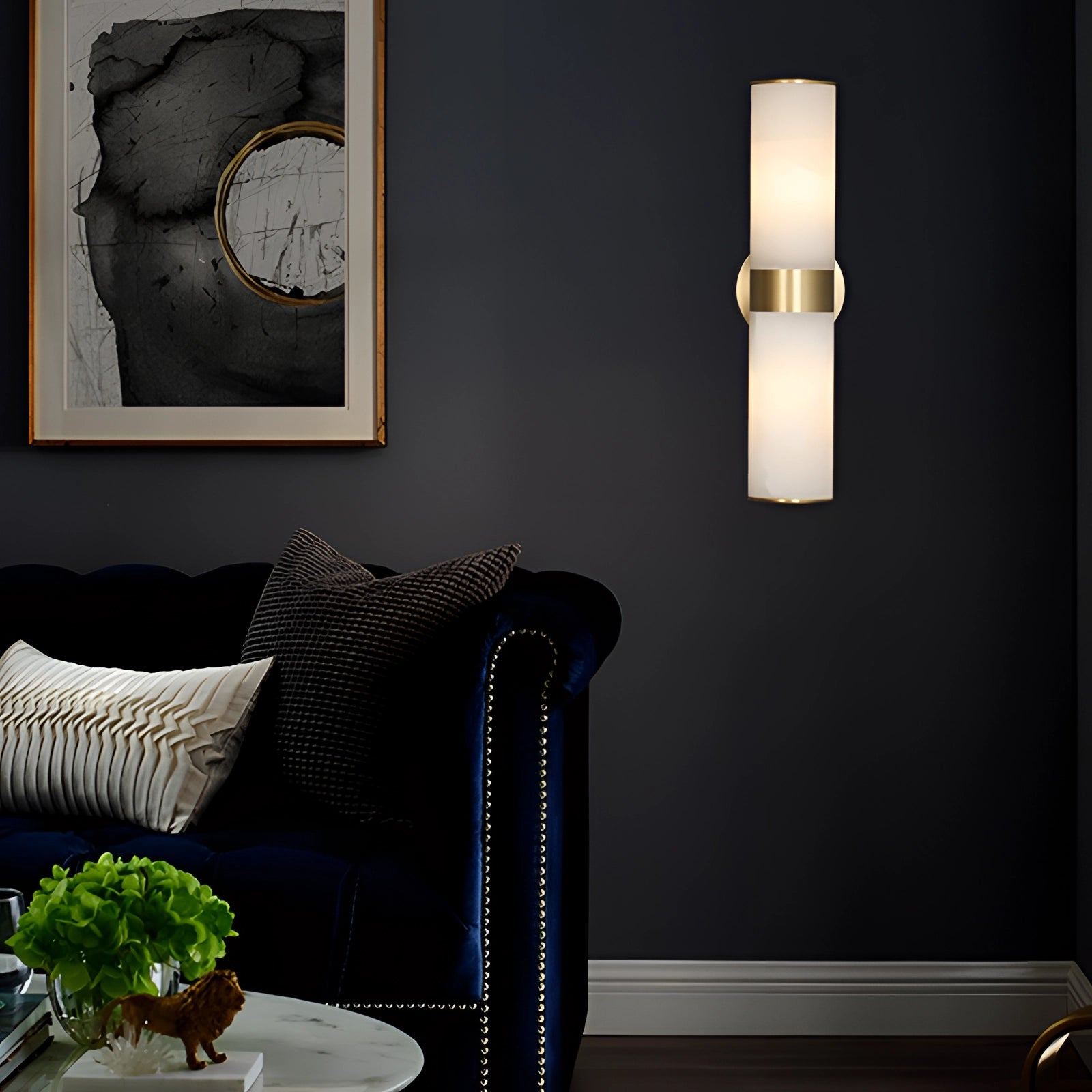 Gold bathroom sconce with cylindrical frosted glass shade, mounted on a brass wall fixture, displayed in a modern interior setting.